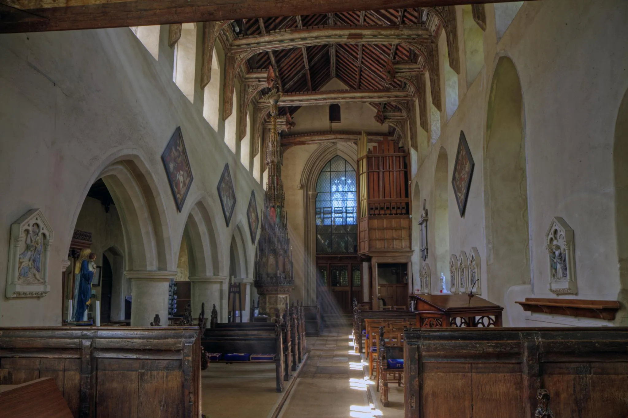 Photo showing: Inside the nave of the parish church of the Assumption of the Blesséd Virgin Mary, Ufford, Suffolk, looking west to the tower arch. Note the tall ornate cover on the font near the west end of the nave.
An HDR image taken with Canon 7D and Canon 17-55mm F2.8 IS lens. AEB +/-3 total of 7 exposures processed with Photomatix. Colors adjusted in PSE 9.