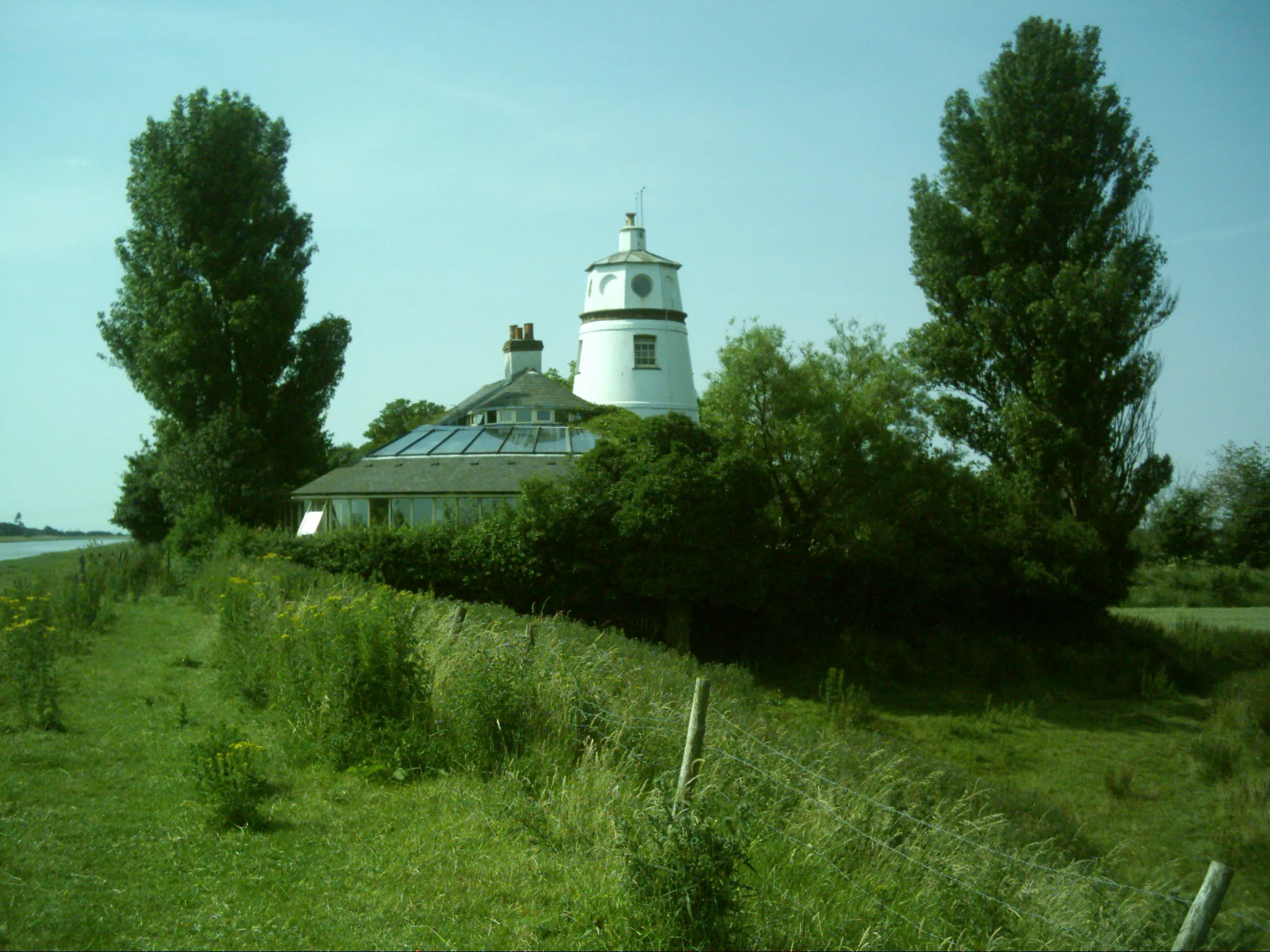 Photo showing: The lighthouse on the West bank of the River Nene stands on the opposite bank to its twin on the East bank. No one seems to know why they are referred to as lighthouses as they never functioned as such. They were built to celebrate the recutting of the Nene Channel where it meets The Wash and acted as markers for ships.
They are now private residences.

LJ RAY 2006