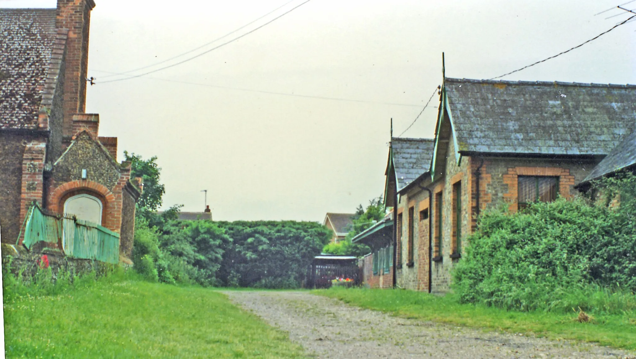Photo showing: Hillington station (remains).
View westward from B1155 road at former level-crossing of the ex-M&GN main line, Soouth Lynn etc. - Melton Constable etc., closed to passengers 2/3/59 but goods traffic continued South Lynn - East Rudham until 6/5/68 and called here until 13/4/65. The station had been the M&GN's 'Royal' station for Sandringham House.