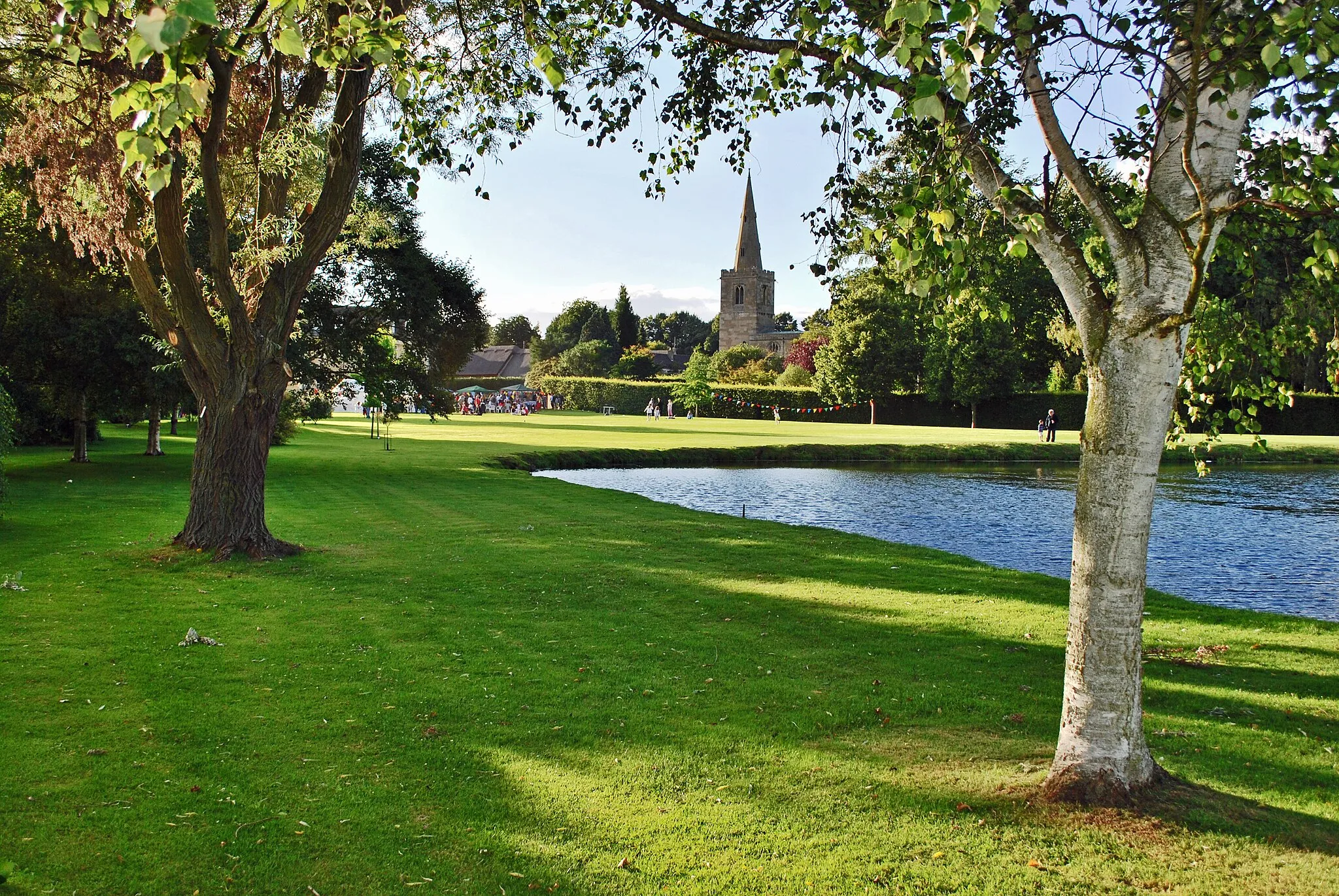 Photo showing: This is a view across the lake at the Manor House looking north-west towards the church.  It was taken at the village fete in July 2008.