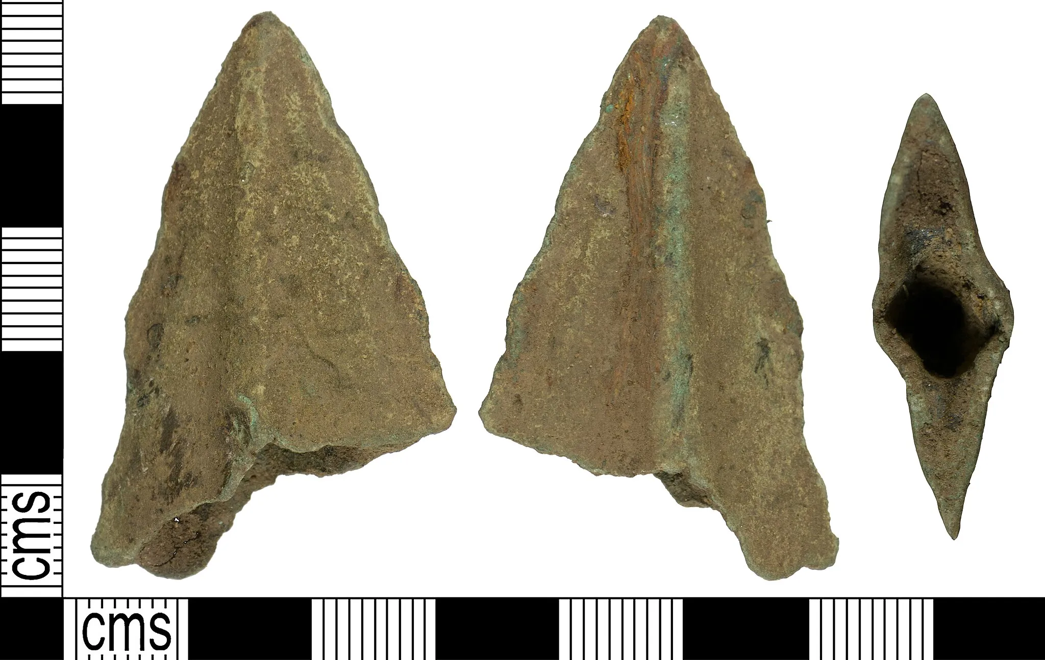 Photo showing: An incomplete copper alloy spear head dating from the Middle to Late Bronze Age, about 1550 – 800 BC. Only the tip of the spear remains which is triangular in shape and lozenge in section. A central rib is present on both faces of the spear extending from the pointed tip to the lozenge terminal end. The blade extends either side of the midrib terminating in abraded edges. The inner portion of the spear head is hollow, in which a wooden shaft would have been fitted. Although insufficient remains to have complete confidence in classifying this object, as the midrib extends to the tip, it is probably comparable with the range of spearheads in Davis Groups 5-11, while its section is possibly most indicative of the Late Bronze Age pegged types, Davis Group 11.
The metal has a mid-green patina and is worn. The spear head is 46.4mm long, 27.3mm wide, 9.2mm thick and weighs 16.1g.
Similar objects recorded on the database are: YORYM-17F9E2 and YORYM-A2E2F3.b