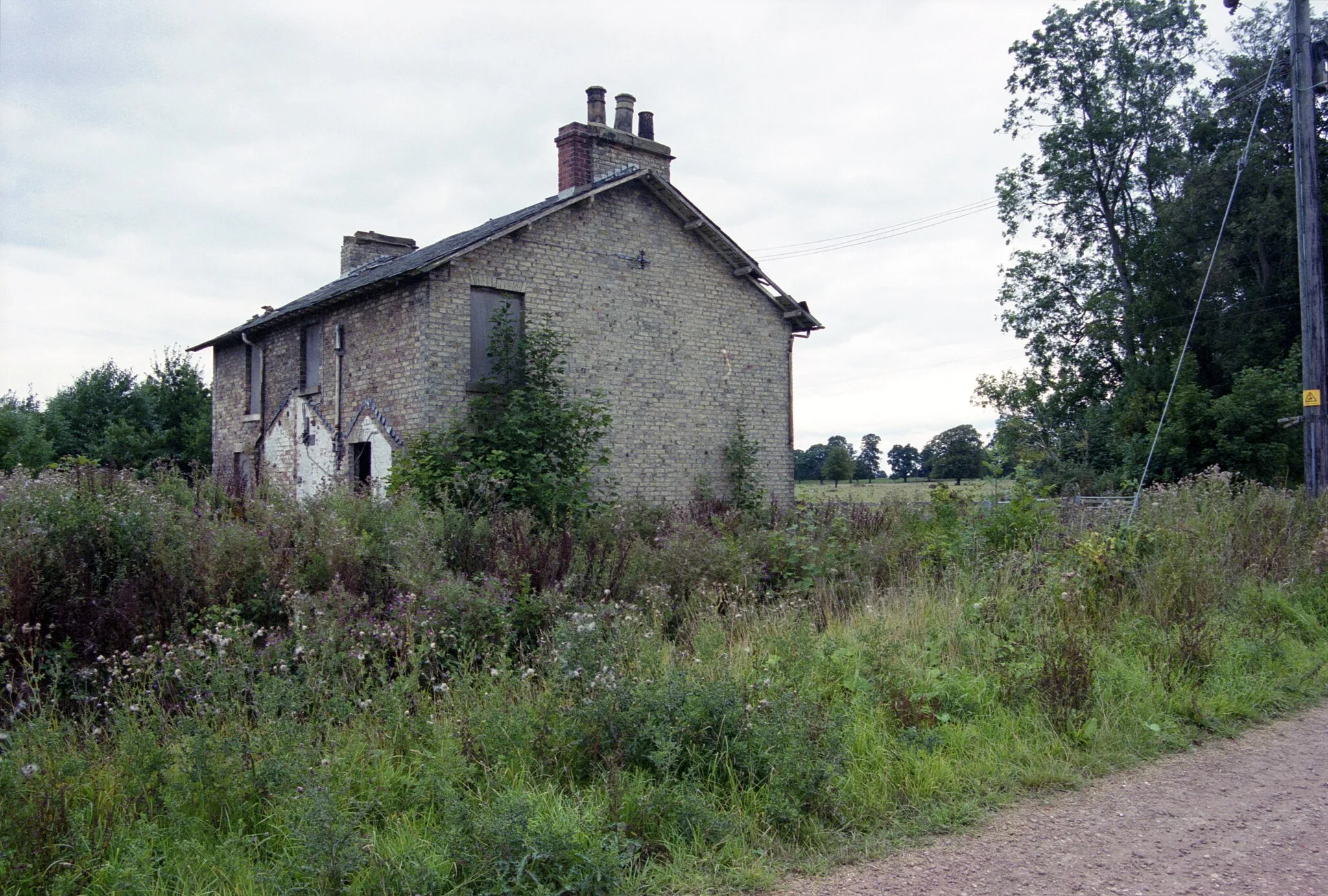 Photo showing: A photographic film image of a dilapidated and overgrown estate farm worker's cottage taken in 1999, at the east of the Sandhall Park estate, south of Skelton in the civil parish of Kilpin, part of the East Riding of Yorkshire, England. The house, occupied before the First World War by the family of an estate garthman (yardman and herdsman), had its own family garden, livestock pens and outbuildings and extensions. Although the house from the one front door appears single occupancy, the back and sides indicates a possible split into two living units. Processing: SLR camera negative scanned with an Epson Perfection V800 scanner and optimized and cropped and spun with Adobe Photoshop CS2.