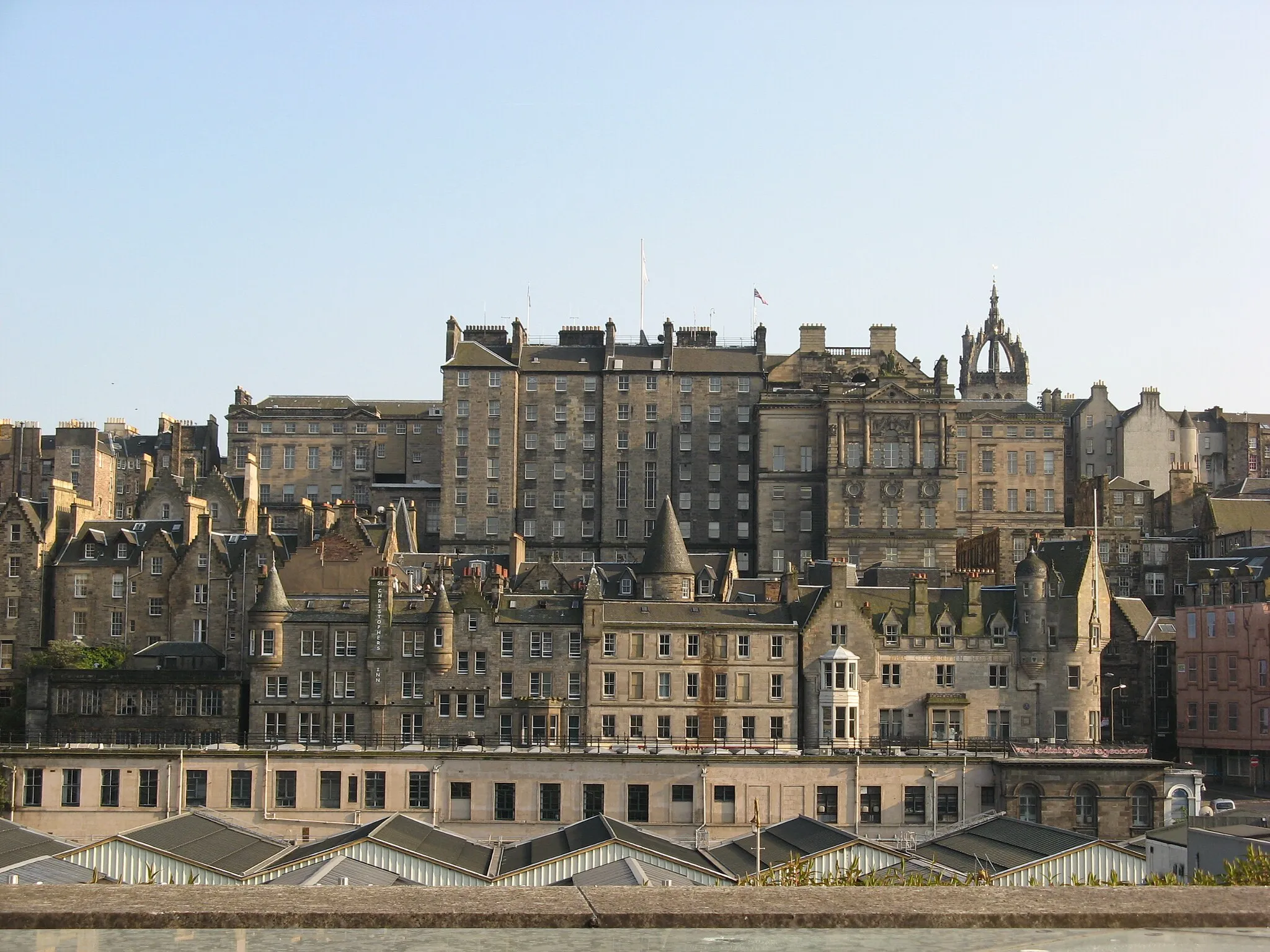Photo showing: View of the Old Town, Edinburgh, from the roof of Princes Mall, on Princes Street. The rear of the City Chambers is in the centre, with the spire of St Giles' on the right. At the bottom is the roof of Waverley Station, with Market Street behind it.
