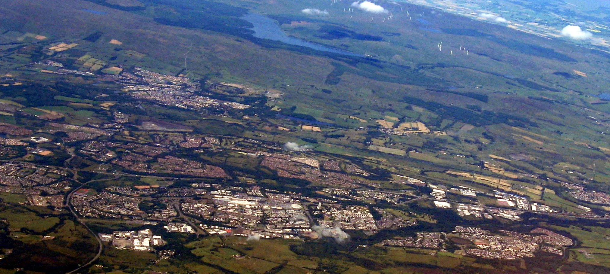 Photo showing: Looking northwest from over North Lanarkshire. The main built-up area across the lower centre is Cumbernauld; beyond and a little left is Kilsyth and beyond that are the Kilsyth Hills and the Carron Valley Reservoir.