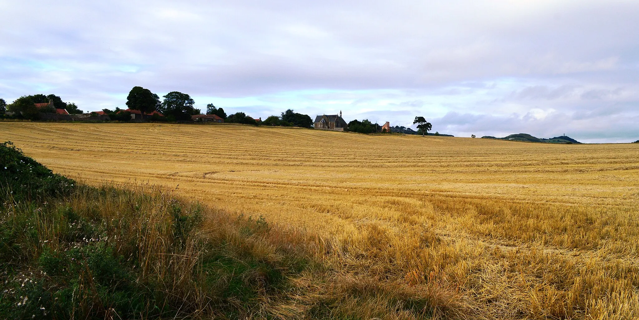 Photo showing: Athelstaneford is a village in East Lothian, Scotland. It lies almost six kilometres north-east of the market town of Haddington and about twenty-eight kilometres east of Edinburgh.
According to popular legend, Athelstaneford is where the original Scottish saltire - a white diagonal cross on a sky blue background - was first adopted. On the eve of a battle between rival armies of Picts and Northumbrians in 832AD, Saint Andrew, who was crucified on a diagonal cross, came to the Pictish King, presumed to be Óengus II, in a vision promising victory. The next morning the Picts saw a white cross formed by clouds in the sky. They won the battle and attributed their victory to the blessing of Saint Andrew, adopting his form of the cross as their flag, and naming him as their patron saint.  Reputedly the leader of the retreating Angles, Athelstan, was said to have been slain at a nearby river crossing, hence the name Athelstaneford. However, it has been postulated that the English leader may have been the English King Æthelstan, who invaded Scotland in AD 934.  Whatever the truth, the legend has cemented Athelstaneford's place in Scotland's history.
The village is home to the ‘National Flag Heritage Centre’ which is situated behind the village kirk (parish church) and occupies a lectern-style doocot built in 1583 and rebuilt in 1996.

The Scotch Mist Gallery contains many photographs of historic buildings, monuments and memorials of Poland.