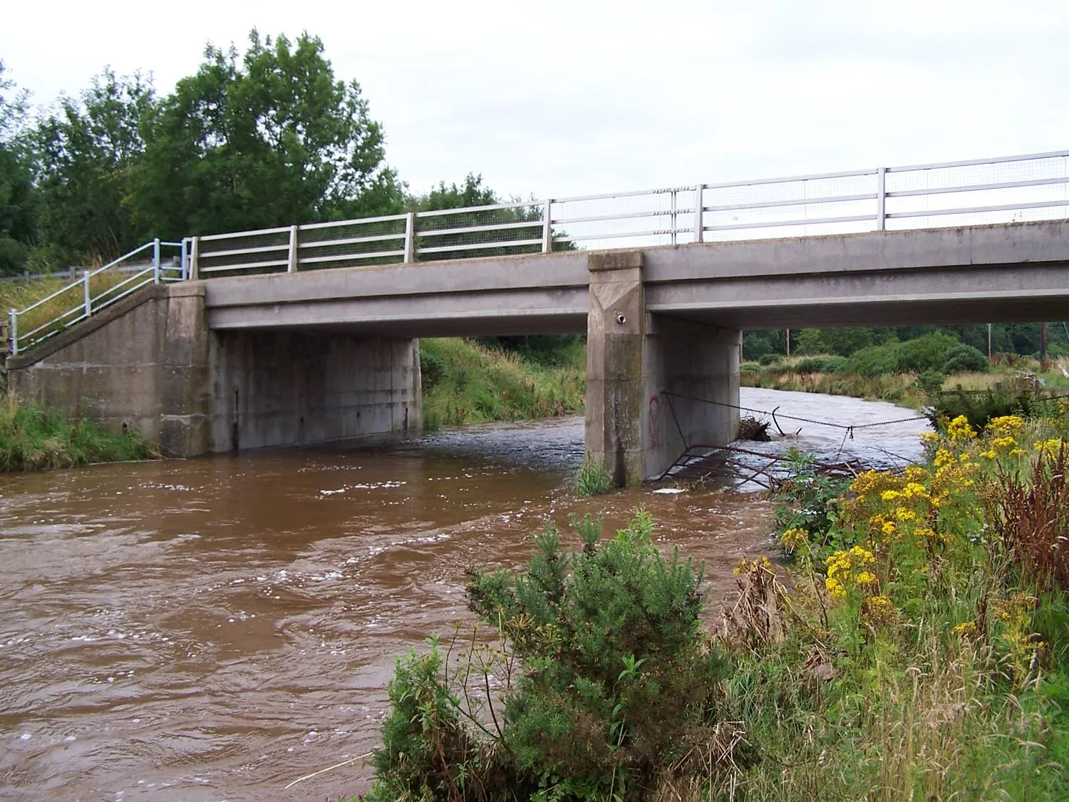 Photo showing: The Eye Water flowing under the bridge carrying the B6438 road at Reston.