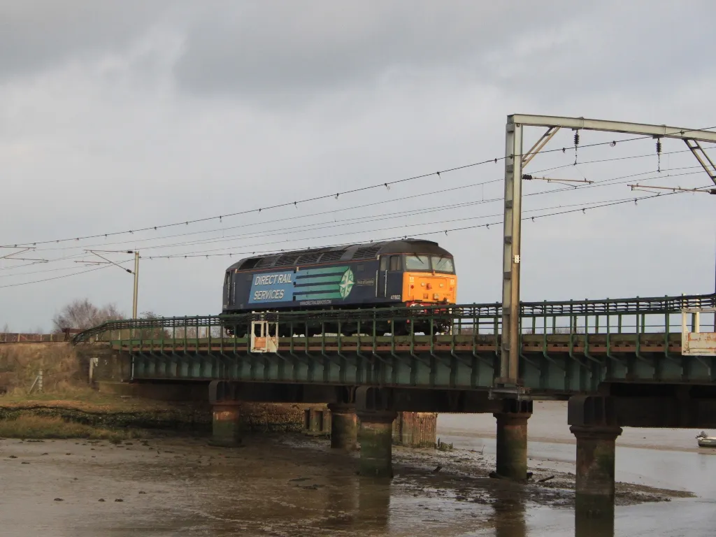 Photo showing: 47802, on 'Thunderbird' duties from Colchester, races north across the Cattawade Viaduct near Manningtree on the Great Eastern Main Line.