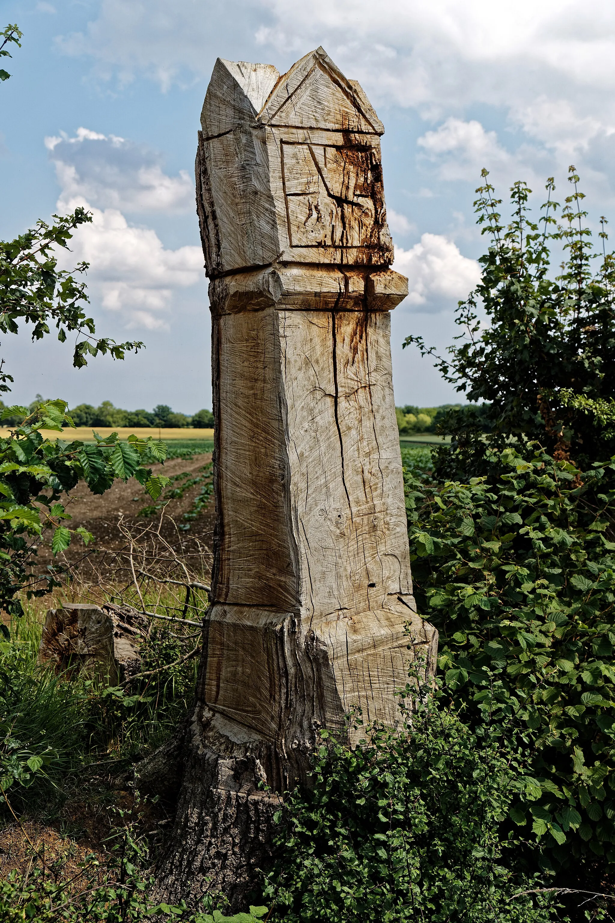 Photo showing: The dead trunk of a roadside oak tree carved by chainsaw into what appears to be imitating a gothic architectural structure, with gables and what looks like a sundial, to the north of Taverners Green in the parish of Hatfield Broad Oak, in Essex, England. Mobile device view: Wikimedia (June 2020) makes it difficult to immediately view photo groups related to this image. To see its most relevant allied photos, click on Hatfield Broad Oak, and this uploader's Photos. You can add a click-through 'categories' button to the very bottom of photo-pages you view by going to settings... three-bar icon top left. Desktop view: Wikimedia (June 2020) makes it difficult to immediately view the helpful category links where you can find images related to this one in a variety of ways; for these go to the very bottom of the page. This image is one of a series of date and/or subject allied consecutive photographs kept in progression or location by file name number and/or time marking. Camera: Canon EOS 6D Mark II with Canon EF 24-105mm F4L IS USM lens. Software: File lens-corrected, optimized, perhaps cropped, with DxO OpticsPro Elite, and likely further optimized with Adobe Photoshop CS2.