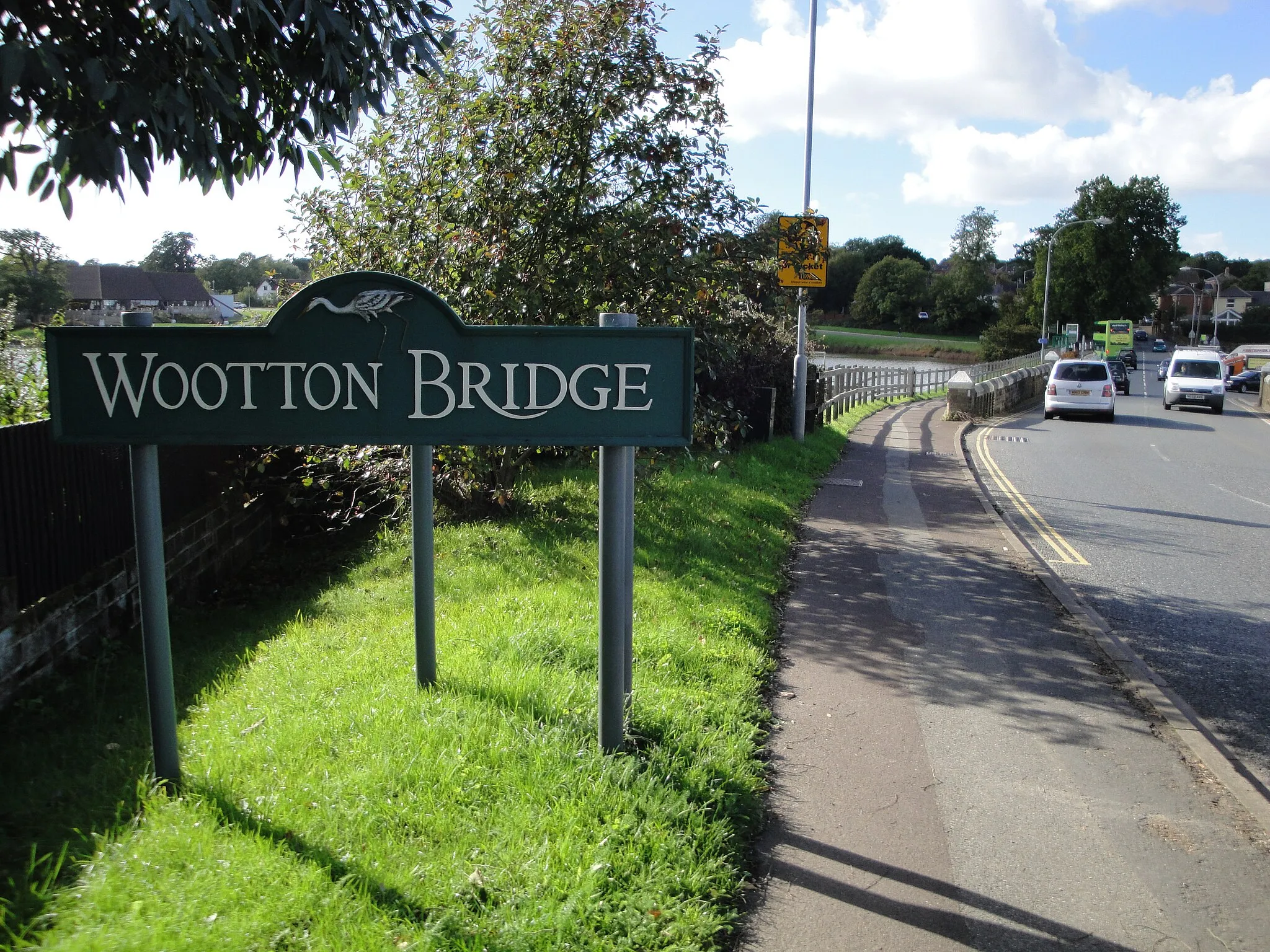 Photo showing: The sign entering Wootton Bridge, Isle of Wight on Kite Hill. The sign has been criticised by some local residents who feel it is in the wrong place and that Wootton also includes much more of Kite Hill than is implyed by the location of the sign. Despite calls for the sign to be moved, it has remained in this location.
