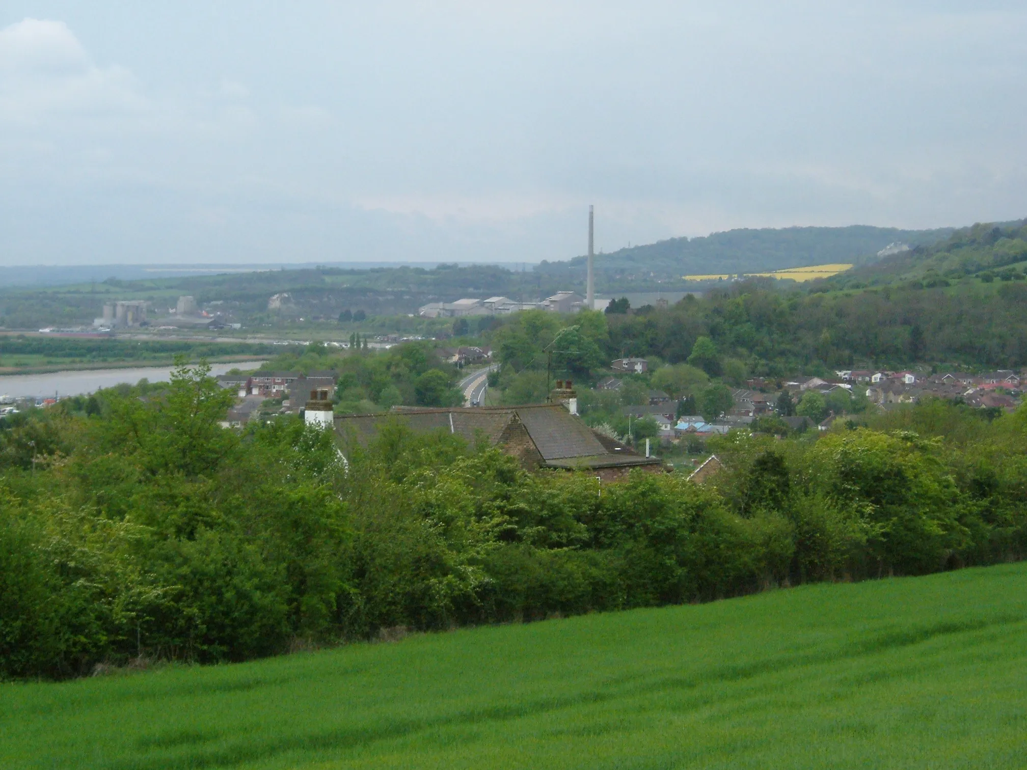 Photo showing: A view of Cuxton, Kent from Ranscombe Farm. The village is sited in a valley in the North Downs leading to the River Medway. In the background is a chimney of the Cement Works at Halling. It is April and the fields are planted with Oil Seed rape giving it the distinctive yellow colour

Camera location 51° 22′ 49.44″ N, 0° 27′ 20.52″ E View this and other nearby images on: OpenStreetMap 51.380400;    0.455700