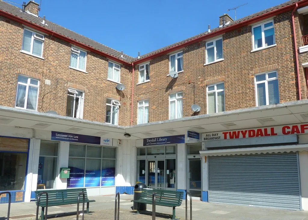 Photo showing: In the corner of a shopping square, empty shop on one side, cafe on the other, flats above.

Update: this library has been refurbished and extended (2016) Must go back and take a new photo!