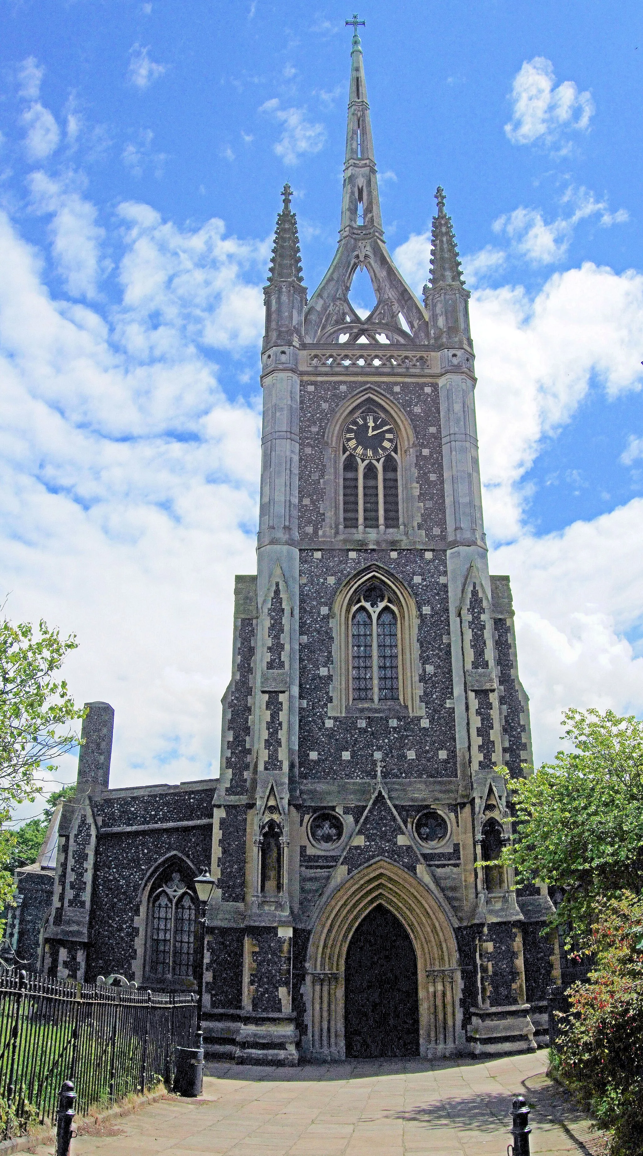 Photo showing: West tower and spire of St Mary of Charity parish church, Faversham, Kent. The tower and spire were built of brick in 1797. They are now encased in stone added by George Gilbert Scott in 1855.