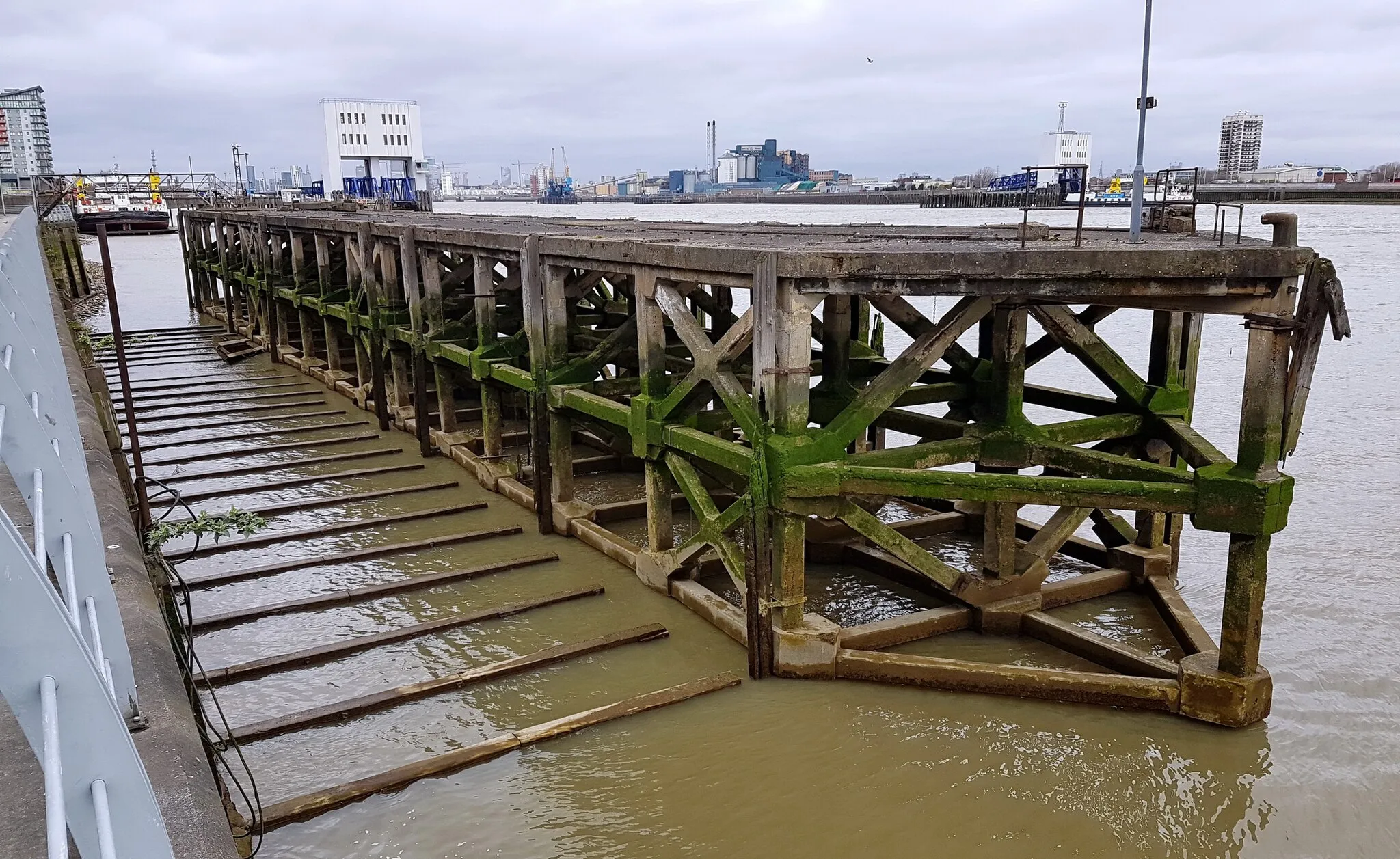 Photo showing: View from the southeast of the coaling jetty built in 1930-31 for Woolwich Power Station. It is all that remains of the power station that once dominated this part of Woolwich Central Riverside. In the background North Woolwich and the Woolwich Ferry.