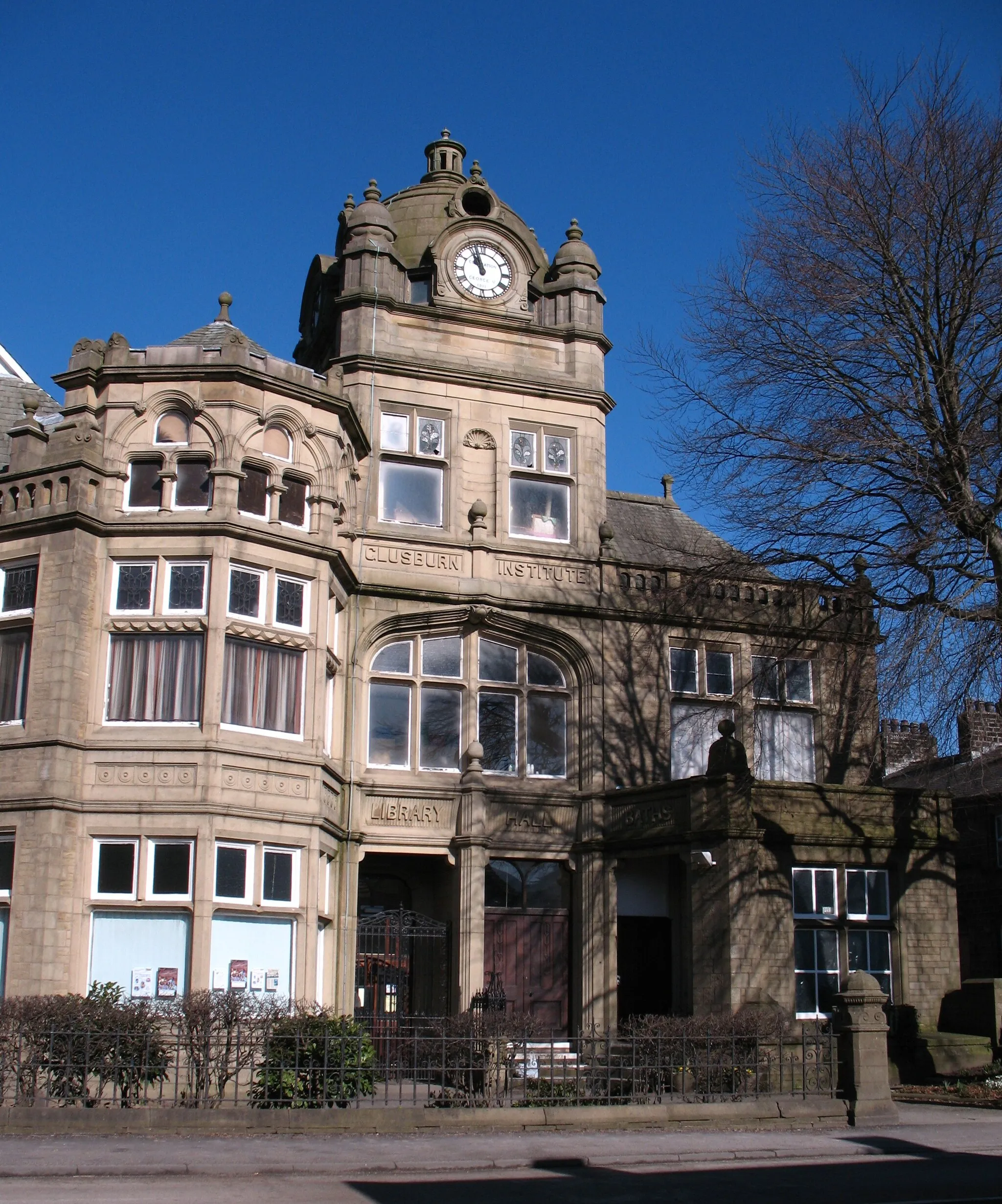 Photo showing: Glusburn Institute A rather splendid public building in the village of Glusburn.  Built over a period of years between 1892 and 1911 [when the clock tower and dome were added] for Sir John Horsfall, local mill owner and benefactor. The building housed an auditorium with stage, dining and reading rooms, a swimming pool and a Baptist chapel.