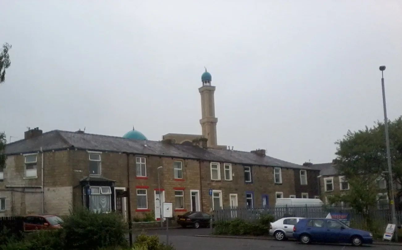 Photo showing: A row of terraced houses in Brierfield, Lancashire. In the background, one can see the tower of the local mosque.