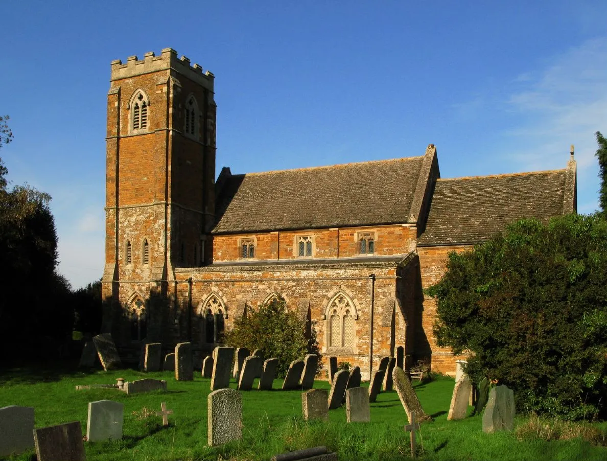 Photo showing: Church of England parish church of St John the Baptist, Bisbrooke, Rutland. The church was built in 1871 and the tower was completed in 1914. The churchyard has a number of Ketton oolite headstones that pre-date the present church.