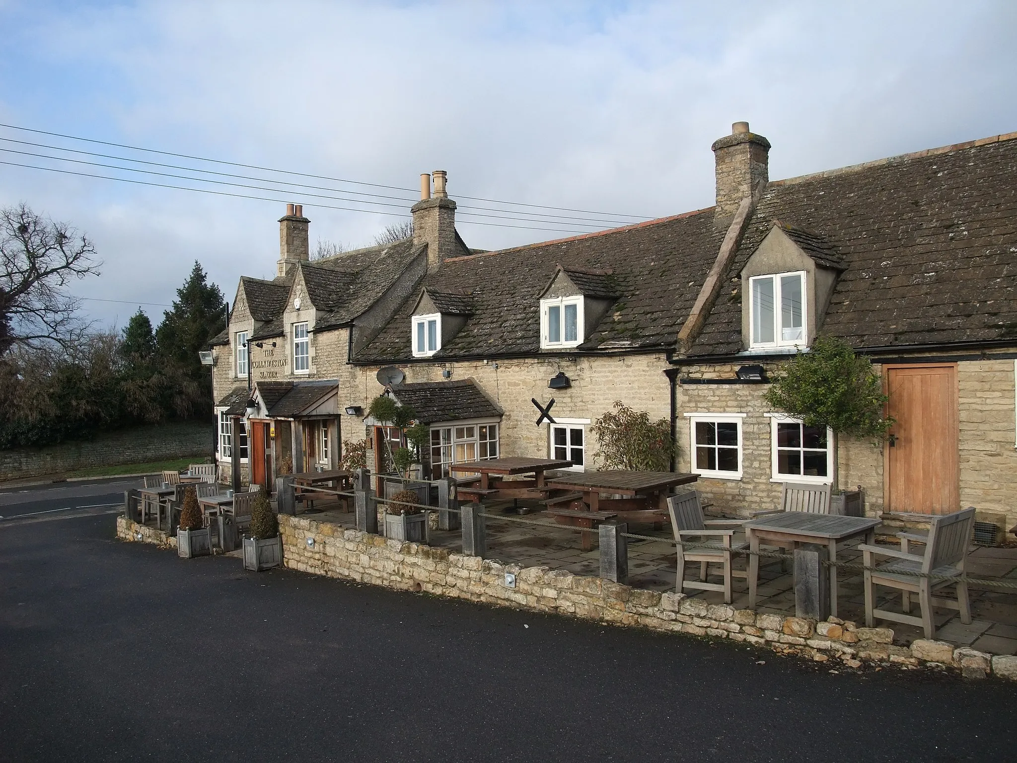 Photo showing: The Collyweston Slater — in Collyweston, northeastern Northamptonshire.
Originally a 17th century coaching inn, extended to include adjoining cottages.
The name refers to the village's importance as a centre for producing Collyweston slate roofs material — roofing slates from the easily cleaved local Jurassic limestone. Very durable, and still popular for traditional stone buildings.