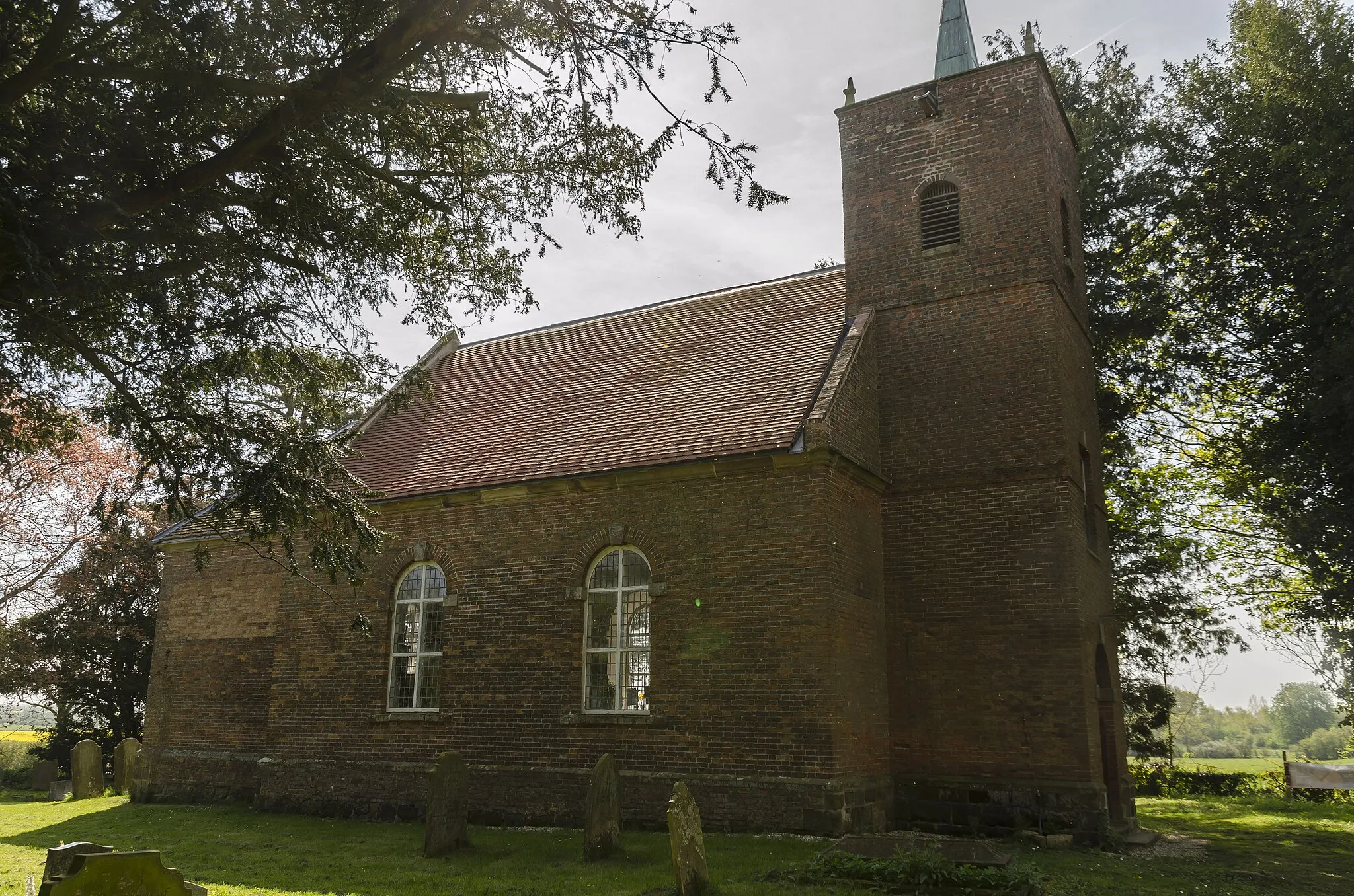 Photo showing: The church was rebuilt in 1754 by Robert Vyner incorporating some of the original medieval work. It is built in redbrick with ashlar dressings, tiled roof and copper steeple.
There is a western tower, nave and chancel.
The three stage tower has reused medieval corner pinnacles. It is topped by a copper clad spire with a weathervane.
The nave has semicircular headed windows to both sides with leaded panes. The chancel east window is also semicircular with stained-glass. The interior is quite light and elegant, and the chancel arch has Ionic Pilasters.
At the west end is a small gallery over the door. The octagonal pulpit is from the 18th century and originally came from Skelton church in West Yorkshire. The church originally had box pews but was re-seated in 1914.
The font is octagonal, 15th century which originally came from Lawton, near Gainsborough.
There is a monument to Sir Thomas Vyner Esquire, a leading banker to Charles II, and on the south side one to Sir Thomas Vyner, former Lord Mayor of London. The monuments were erected in 1672.

The banker is shown in full wig and gown and the mayor wears his chain of office. Both of them were carved in 1673 by Jasper Latham. The tombs were removed from Saint Mary Woolnoth church, London by Sir Robert Vyner when the church was built in 1756. There is also a memorial to Frederick Vyner, who was "murdered by brigands in the Kingdom of Greece".