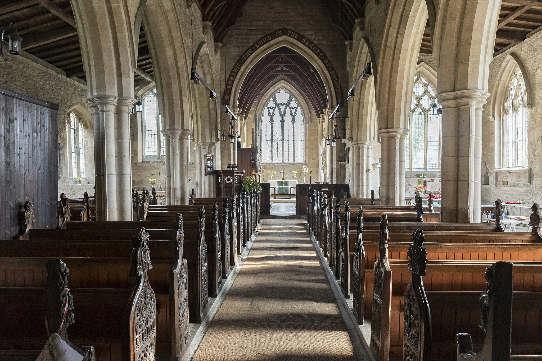 Photo showing: The Domesday Survey records a church on this site in 1086 in the possession of Gilbert of Ghent the wealthiest landowner on the county at that time.
The present church dates from the twelfth century onwards and consists of a western tower, nave with north and south aisles, chancel, and south porch.
The west end of the church is probably the oldest part dating from 12th or early 13th century with walls made of rubble which is 8ft thick in places. The South aisle once extended to embrace the tower but this section was demolished. Most of the church was constructed in 1320 with the nave, south aisle chancel and porch being rebuilt at this time.
The western tower is from the thirteenth century and is of three stages with a plain parapet. The belfry stage has fourteenth century windows.
The south porch, dating from the fourteenth century has arcading above the side benches with ogee headed panels.
The nave has four bay arcades with thirteenth century octagonal piers. At the east end of the south aisle there is a door which once led to the rood loft. Only the lower portion of the rood screen remains at Osbournby.
There is one modern stained-glass window to the north wall.
The chancel has a fine fourteenth century sedilia with ogee arched heads and Crocketts with human head stops. There is also a piscina and aumbry.
The nave has a number of good fourteenth century bench ends with various subjects including Adam and Eve, and St George and the Dragon.
There is a twelfth century tub font with intersecting blank arcading, presumably from an earlier church.
At the south west end of the nave there are commandment boards.
There is a small organ by Harston of Newark, circa 1890.
The church was restored in 1873 by Charles Kirk when the roof was replaced and the east window and pews were installed (cost £1,460).

In 1965 the tower was found to be dangerously cracked and bulging and had to be strengthened. The clock which was removed from the tower face dates from 1740 and now resides in the North Aisle.