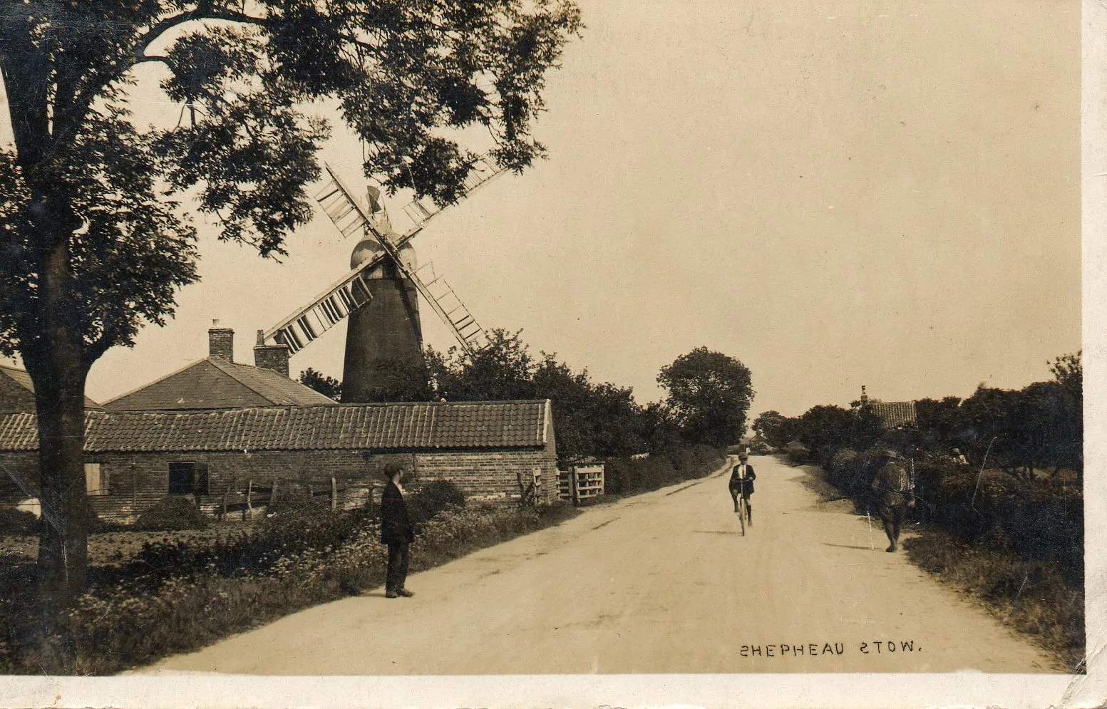Photo showing: Drove Road, Shepeau Stow, Lincolnshire, with Lawson's Mill on the left. Postcard postmarked 1921. Publisher not identified.