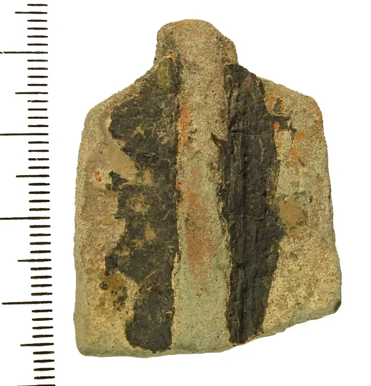 Photo showing: Fragment of a copper alloy vessel or tripod leg.   The reverse is flat and the face is vertically ribbed.  The object is broken at either end.  There is soot on the surface.