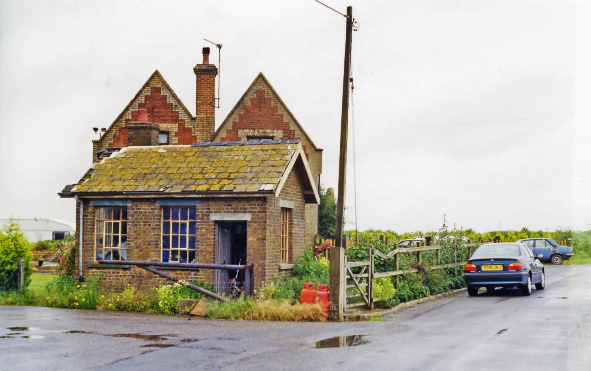 Photo showing: Site/remains of Emneth station, 1998.
View northward at the former level-crossing: Emneth station was miles from anywhere, in the middle of the Fens east of Wisbech on the Great Eastern line from March via Wisbech to Magdalen Road (now Watlington) on the Ely - King's Lynn main line. The line was closed east of Wisbech on 9/9/68, but March - Wisbech has remained open for goods. (THere seems to be no trace of the line here on modern OS maps).