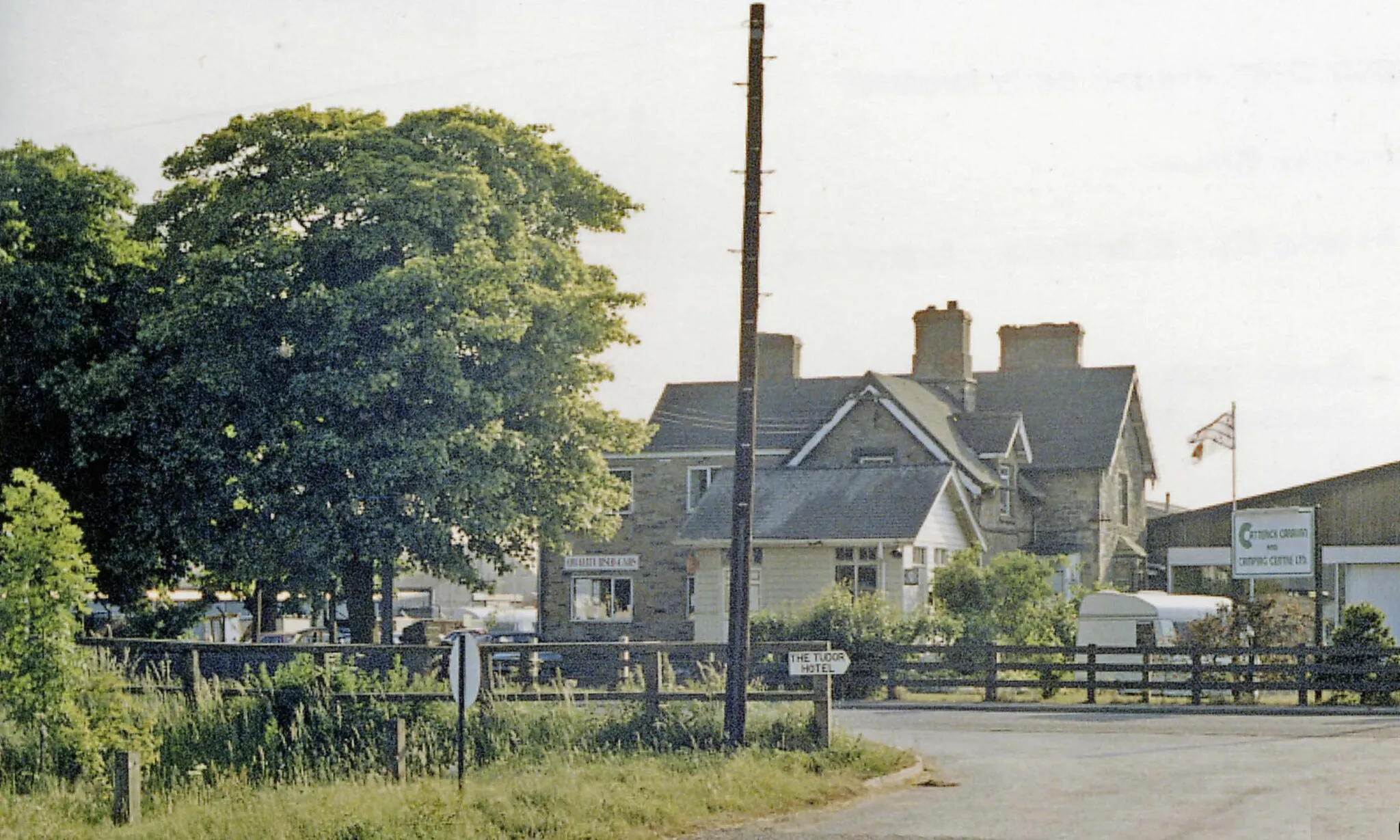 Photo showing: Catterick Bridge station (remains), 1988.
View westward, towards Richmond: ex-NER (Darlington) - Eryholme Junction - Richmond line. The station, also the Catterick Military Railway which branched off to the SW, served the vast Military Camp - the largest of the British Army, with 12,000 men - and therefore important, even after World War Two, the branch seeing regular Troop and Leave trains. However, it and the line to Richmond were closed to passengers from 3/3/69 and to goods from 9/2/70. The track, now a roadway, was lifted in October 1970. (The Goods Yard was the scene of a major explosion of ammunition in February 1944).