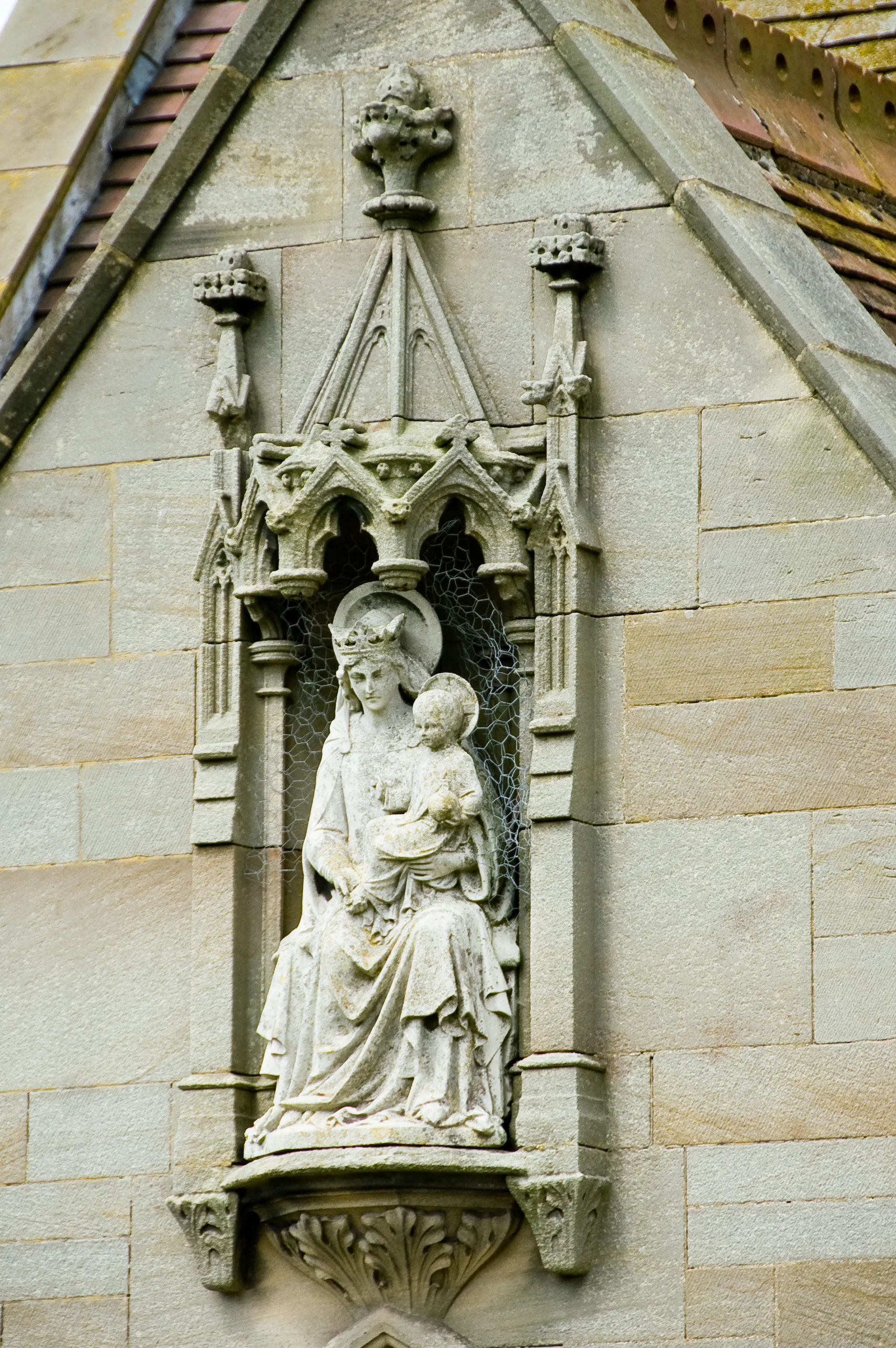 Photo showing: St Mary from West Lutton in North Yorkshire  1872-3 : George Edmund Street.

S porch, Madonna & child, by James Redfern, 1875: James Redfern from the church in Kirby Grindalythe Yorkshire. James Frank Redfern (1838-1876), sculptor, was born at Hartington, Derbyshire, in 1838. As a boy he showed a taste for art by carving and modelling from the woodcuts of illustrated papers. At the suggestion of the vicar of Hartington, he executed in alabaster a group of a warrior and a dead horse. This was brought to the notice of Alexander Beresford-Hope, on whose estate Redfern was born. Hope sent him to Paris to study for six months. His first work exhibited at the Royal Academy, Cain and Abel (1859), attracted the notice of John Henry Foley. He exhibited a Holy Family in 1861, The Good Samaritan in 1863, and other subjects almost every year until his death. These were at first chiefly of a sacred character, and afterwards portrait statues. His larger works were principally designed for Gothic church decoration.