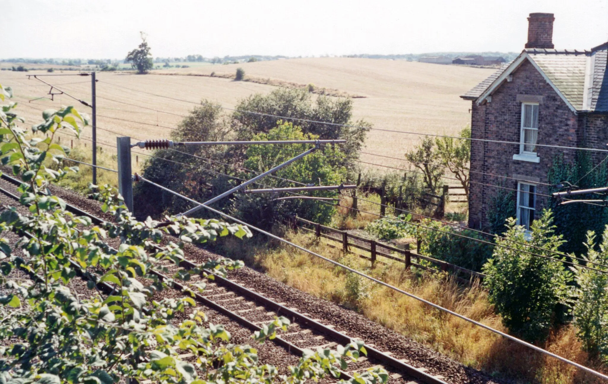 Photo showing: Site of Danby Wiske station, ECML 1991.
View southward, towards Northallerton, York etc.: ex-NER section of the East Coast Main Line, electrified 1989. The small wayside station was closed 15/9/58. The house on the right may have been the station house.