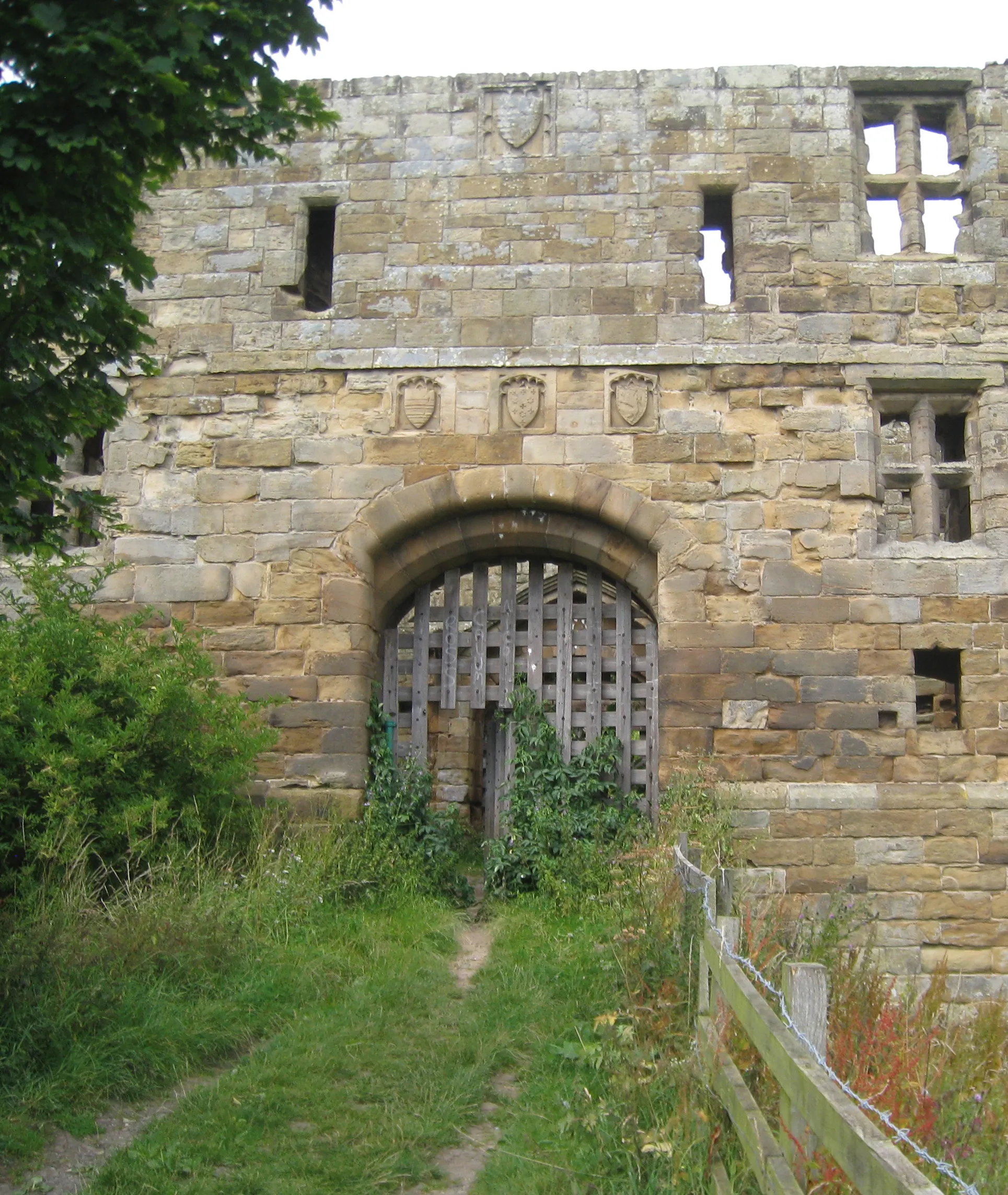 Photo showing: East (main) entrance to Whorlton Castle, North Yorkshire. The shields above the entrance present the arms of Darcy (centre) flanked by Meynell (right) and Gray (left). Above is a further single shield that shows the arms of Darcy and Meynell impaled.