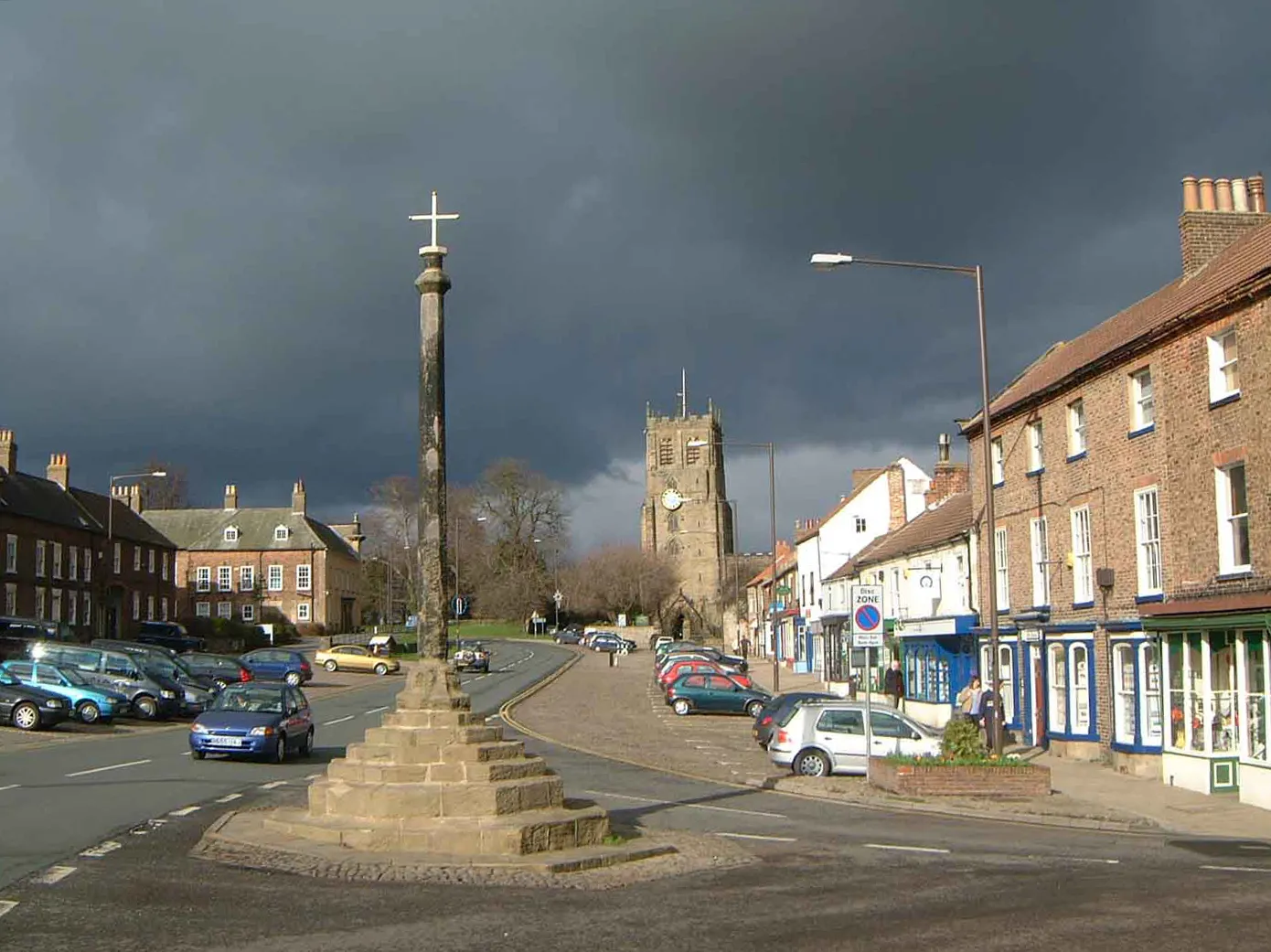 Photo showing: Market cross in Bedale, North Yorkshire, at the junction of North End and Market Place. In the background is the west tower of St Andrew's parish church.