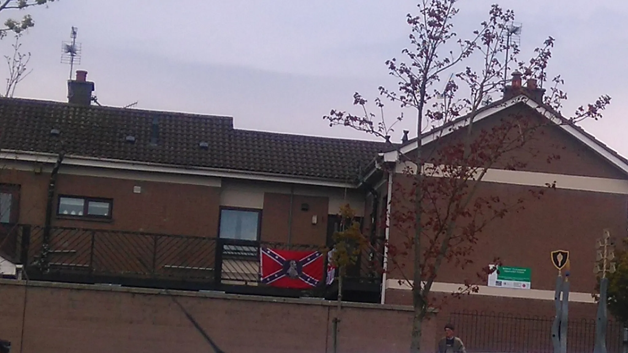 Photo showing: Seen attached to the rear deck of some flats in Ballykeel, along with an Ulster Banner.