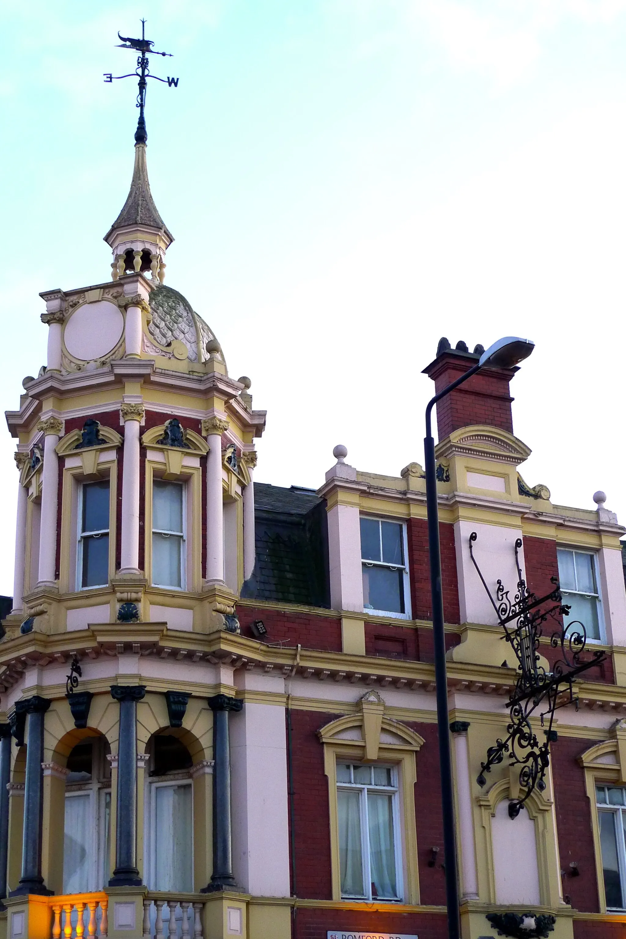 Photo showing: Some nice ironwork (presumably to support a no-longer-extant hanging sign) and a weathervane on this grand pub building. (View of building.)