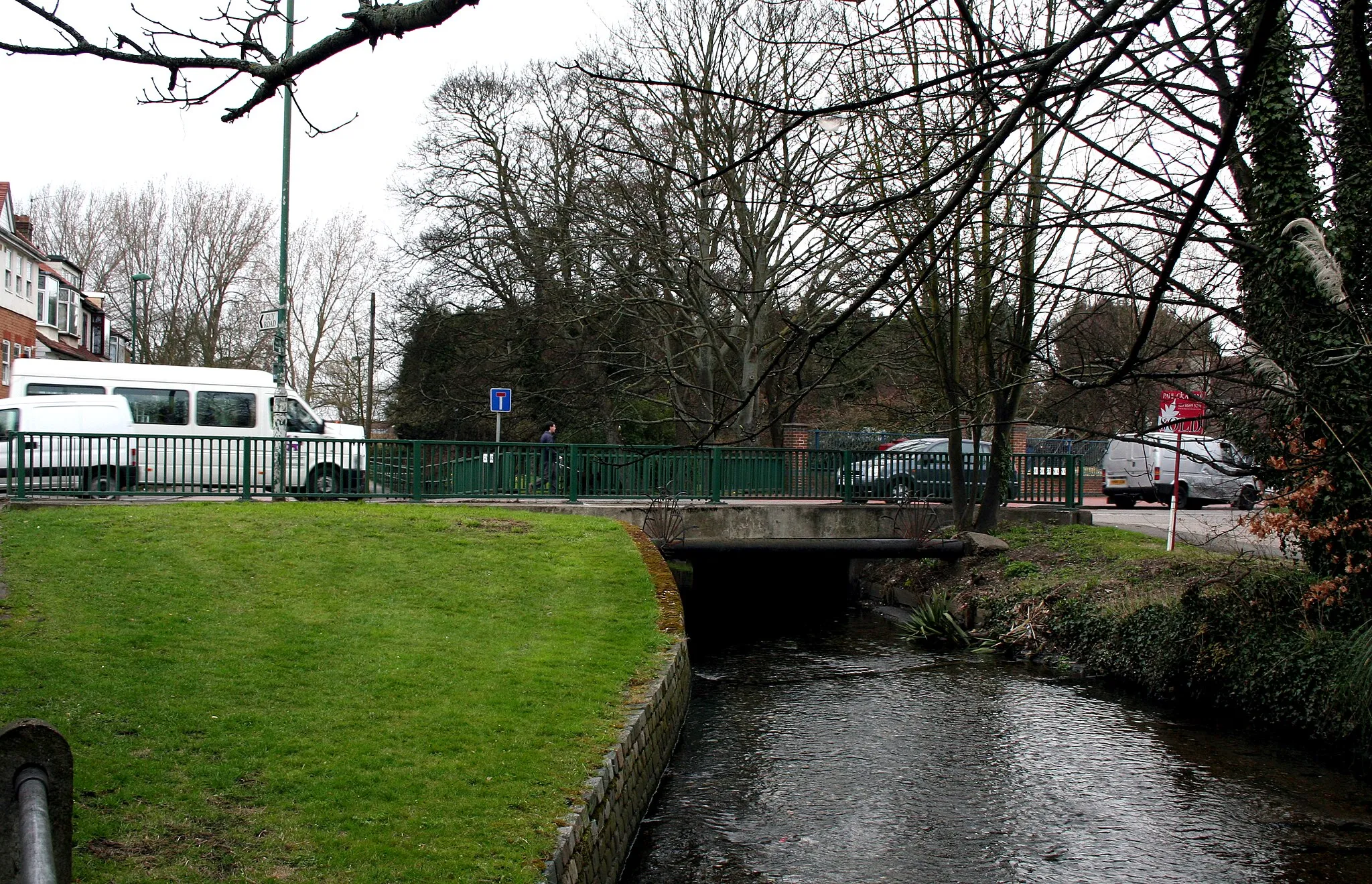 Photo showing: Beddington:  Bridge over the River Wandle Looking downstream (west) here, we see the bridge by which the busy B272 crosses the River Wandle.  North of here, this road is called Beddington Lane, while southwards it is Hilliers Lane.
