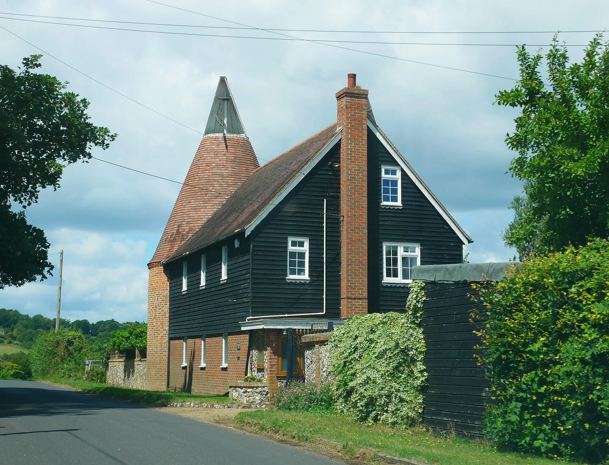 Photo showing: An oast house on the (apparently unnamed) road running east out of Well Hill in Sevenoaks District, Kent, toward Lullingstone. The building in question is on the north side of the road, a short distance west of where the road is joined by Cockerhurst Road coming up from the south