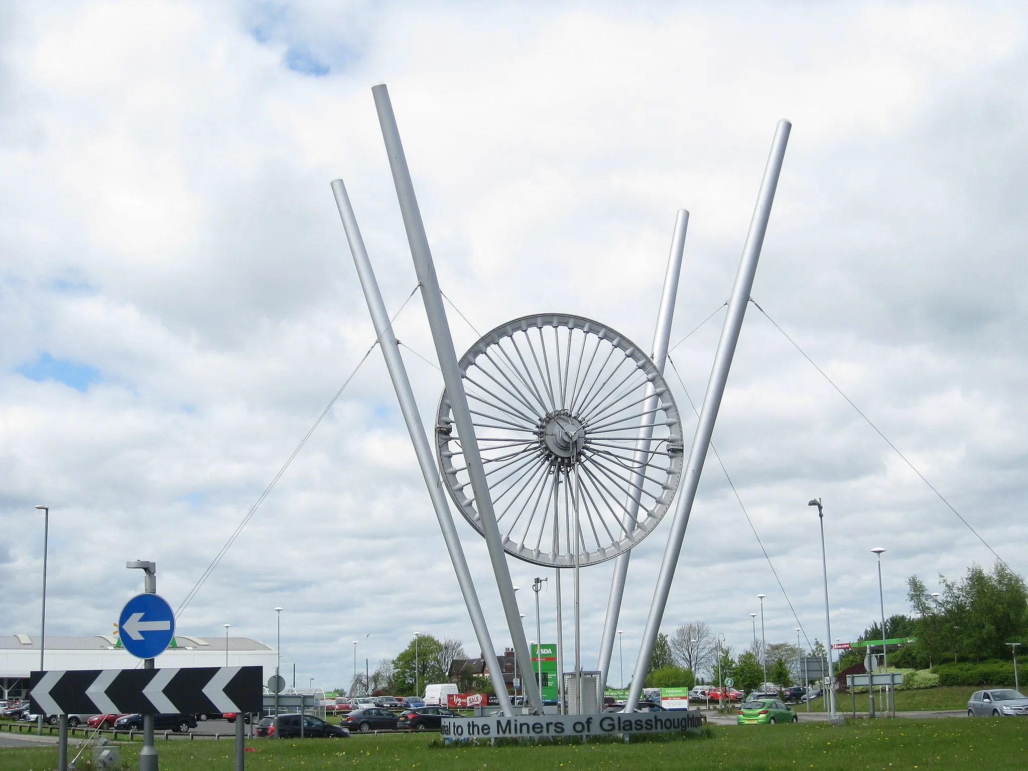 Photo showing: Glasshoughton Wheel of Light.  A former pit winding wheel, now a memorial to the miners of Glasshoughton, on  a roundabout at the junction of the A639 and the A6539.