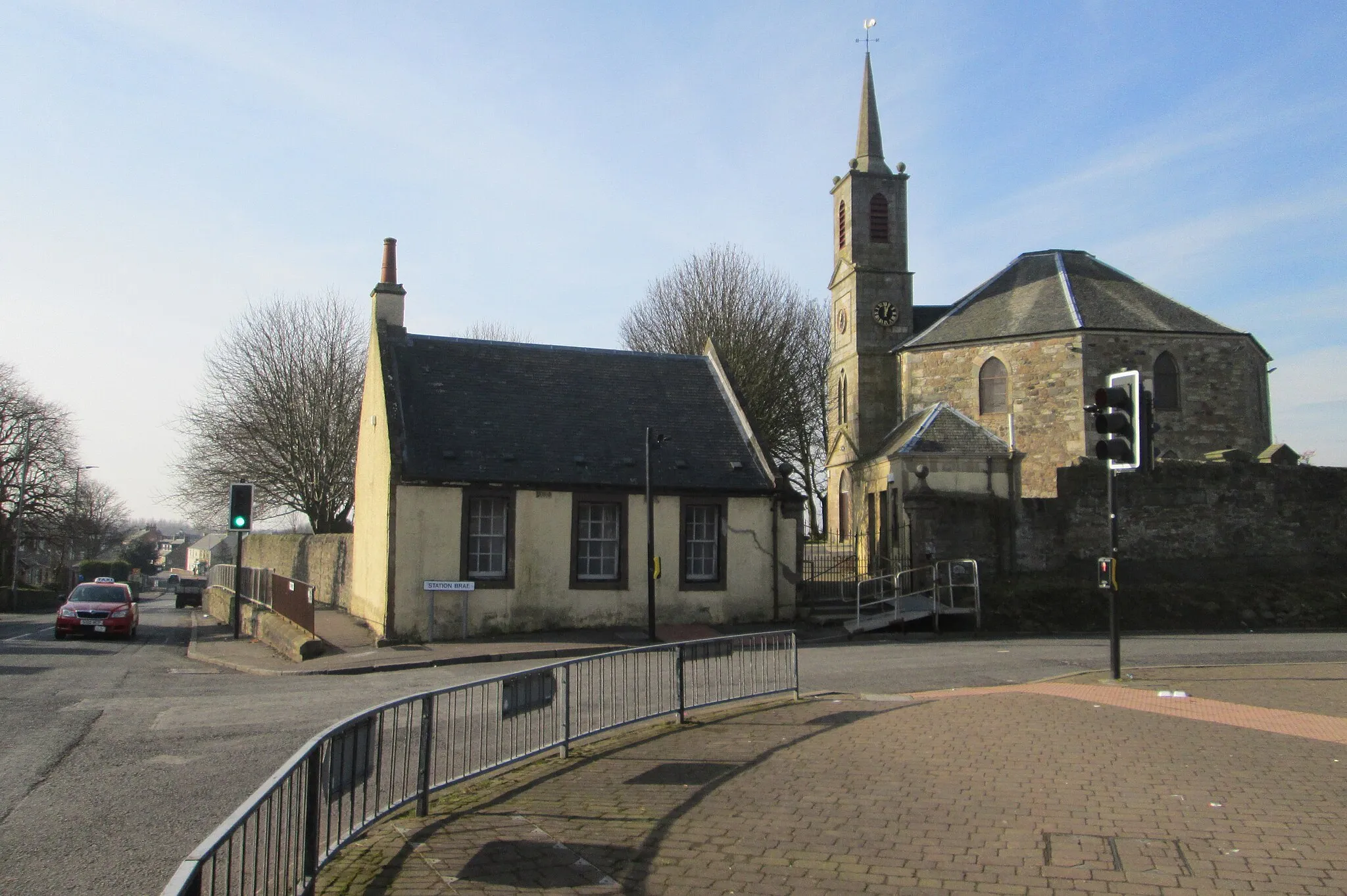 Photo showing: Dreghorn crossroads, looking down Townfoot (B7081) with the old Post office and Dreghorn and Springside Parish Church at the corner of Station Brae