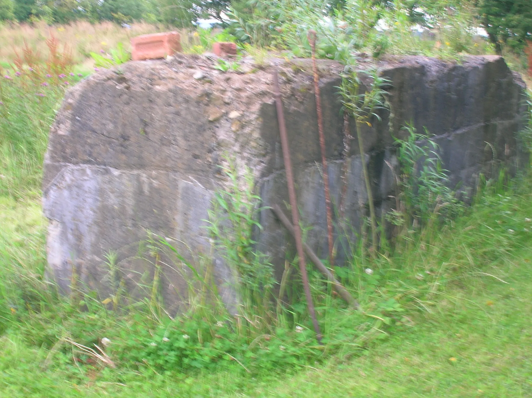 Photo showing: A concrete plinth for heavy machinery, with a quarry drill leaning against it at Auchenmade brickworks in Auchentiber, North Ayrshire, Scotland.