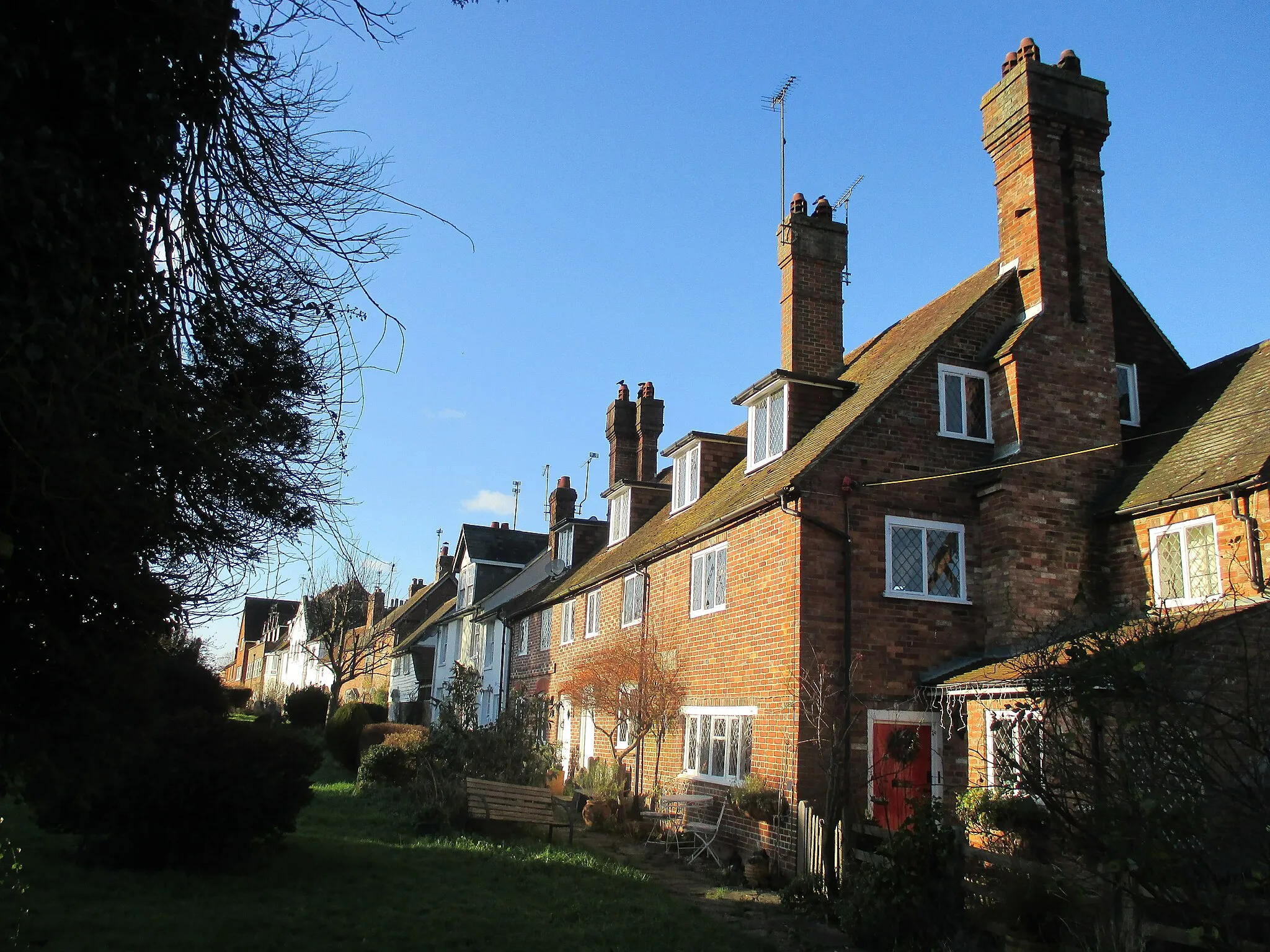 Photo showing: Rear view of houses on the south side of Station Road, Cowfold, West Sussex, backing onto Cowfold churchyard, photographed from the south-east.