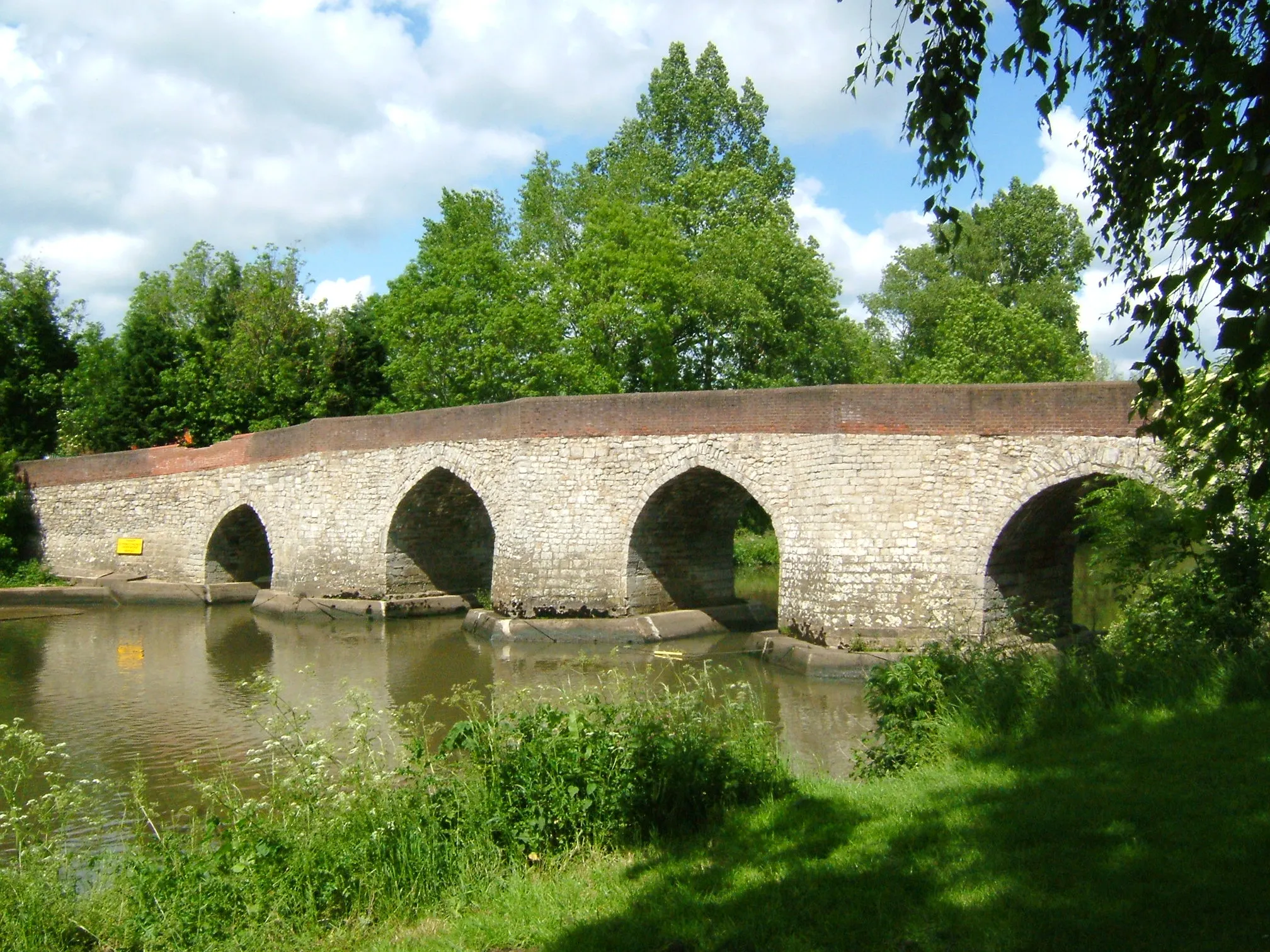 Photo showing: Twyford Bridge on the River Medway near Yalding, Kent. It is just downstream of the automatic sluice where the river drops from +11.2m to +7.41m above mean sea level. The navigation bears left through Hampstead Road Canal and Hampstead Lock; the main stream drops over the weir and sluice and is joined by the River Teise (Lesser Teise) and both pass under Twyford Bridge. The river then flows in a loop towards Yalding, where it is joined by the River Beult which has been joined by the River Teise (the other bit!) and has passed under Town Bridge. Twyford Bridge is not navigable. Twyford bridge is 10 miles from Allington.