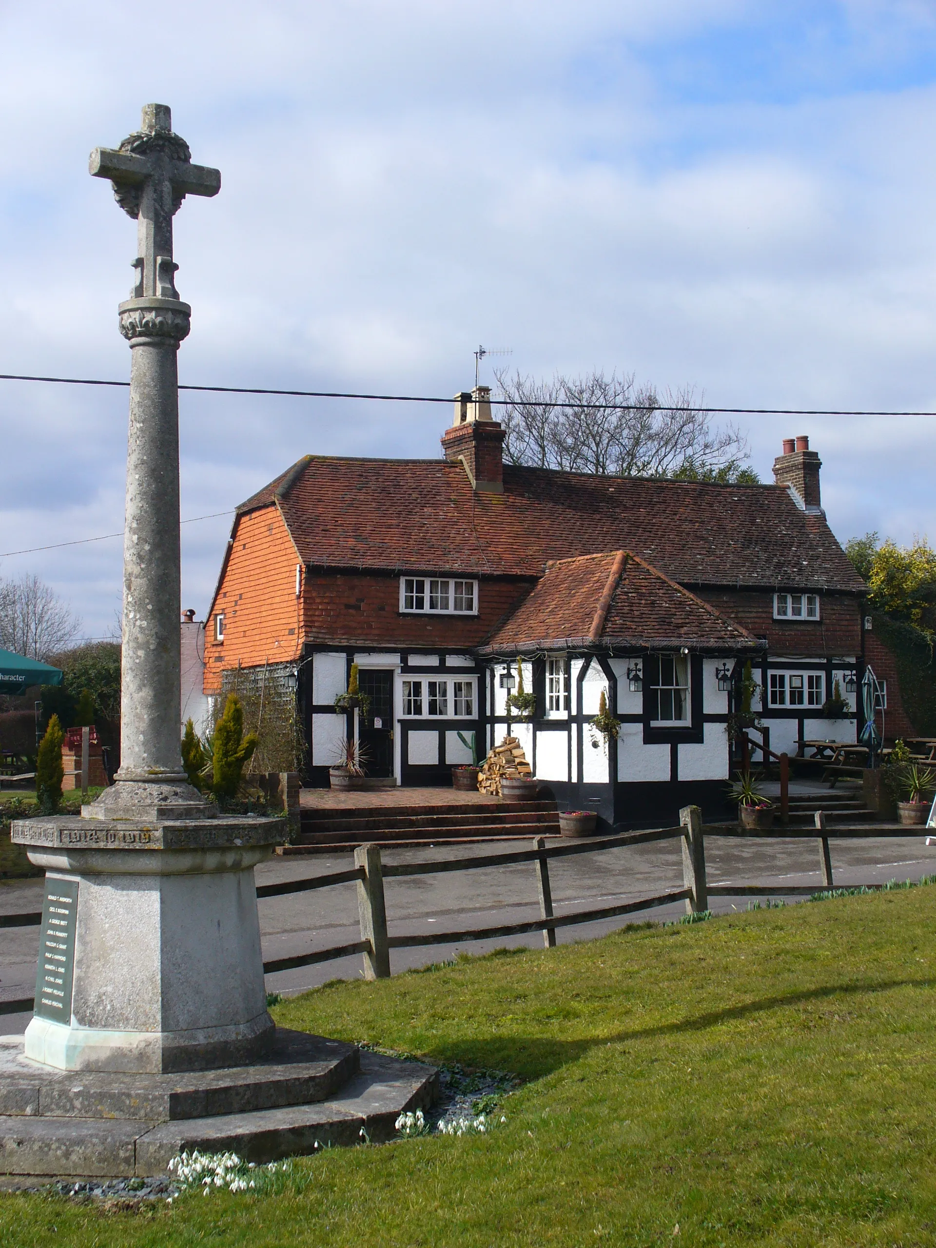 Photo showing: Newdigate War Memorial Outside St Peter, the parish church - with the Six Bells pub across the street. The pub takes its name from the six bells in the church.