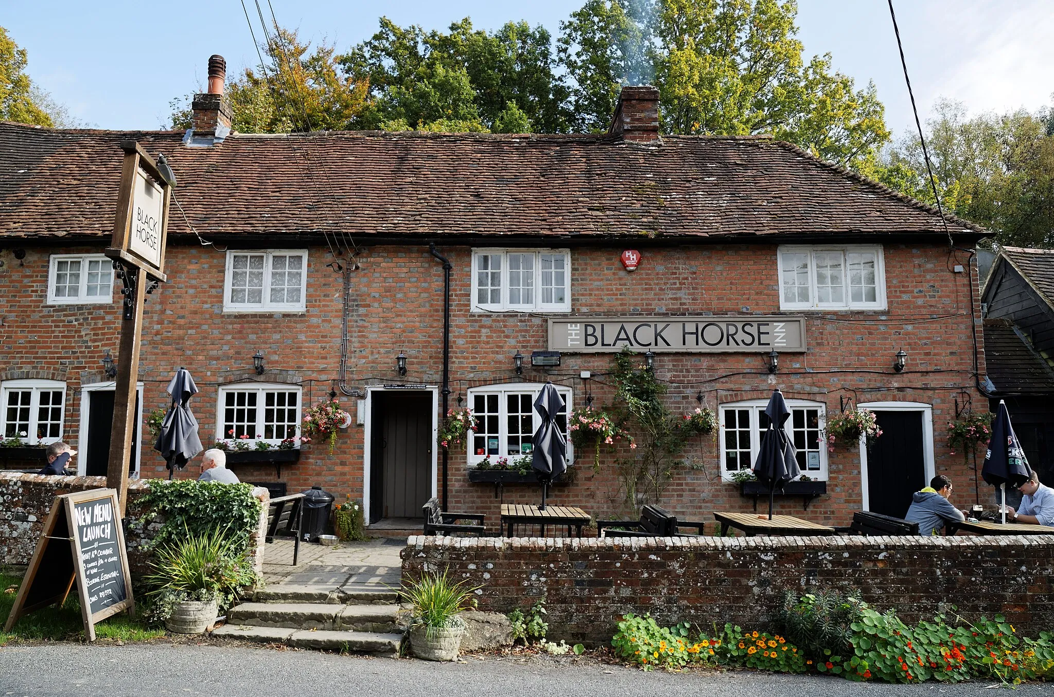 Photo showing: The Black Horse Inn public house, one of Sussex's most haunted pubs, on Nuthurst Street in Nuthurst, West Sussex, England. The Black Horse Inn, reputedly haunted by a local murderer who drank here (see 'Haunted table' of The Black Horse Inn), is part of the 17th-century Black Horse Cottages Grade II listed buildings. Software: RAW file lens-corrected, optimized and converted to JPEG with DxO OpticsPro 10 Elite, and likely further optimized and/or cropped and/or spun with Adobe Photoshop CS2.