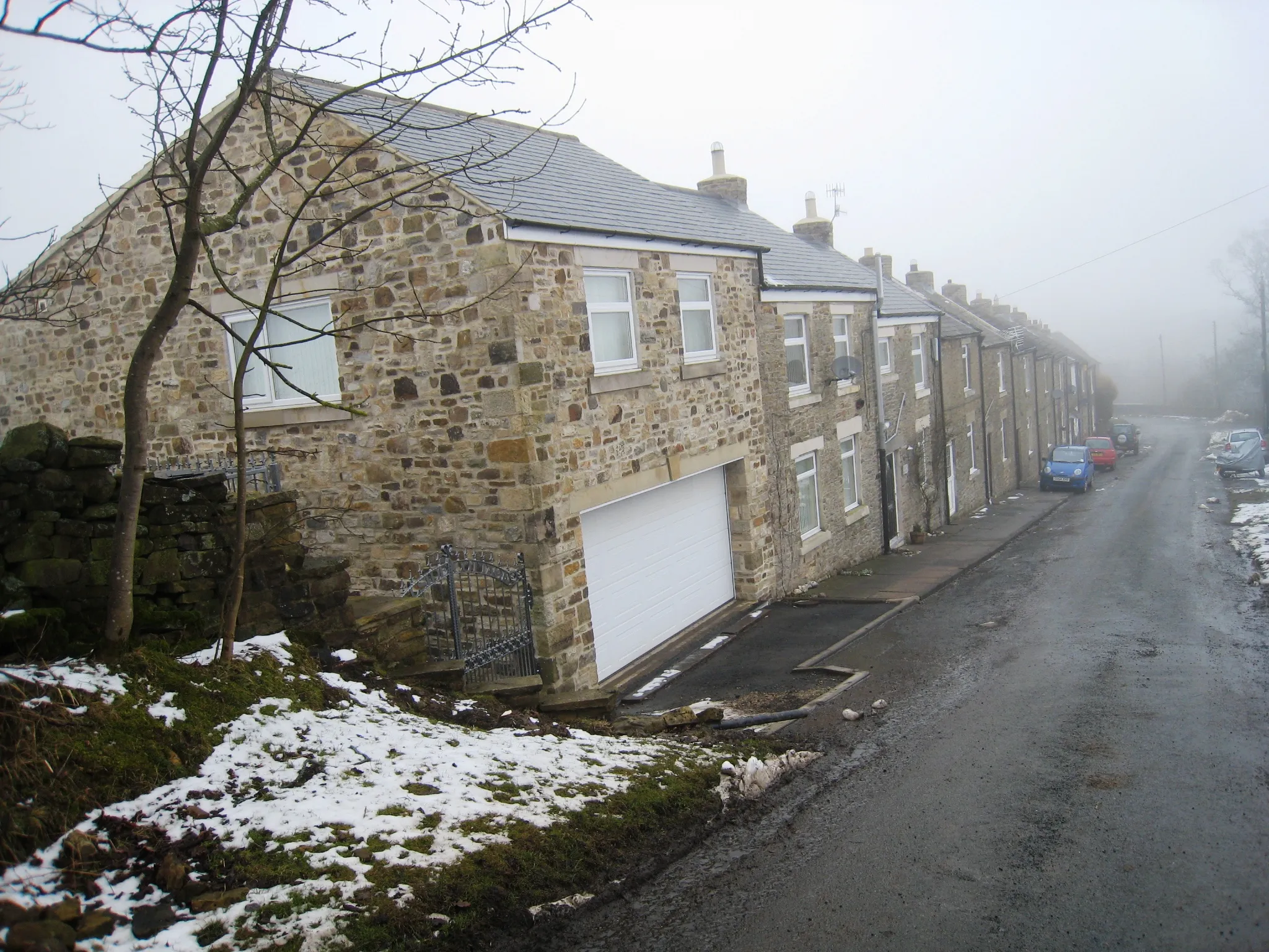 Photo showing: Houses in White Kirkley This photograph shows a view of some of the houses on the downhill section of the road through White Kirkley. The picture was taken on a misty day in late February looking in a northerly direction towards Frosterly.