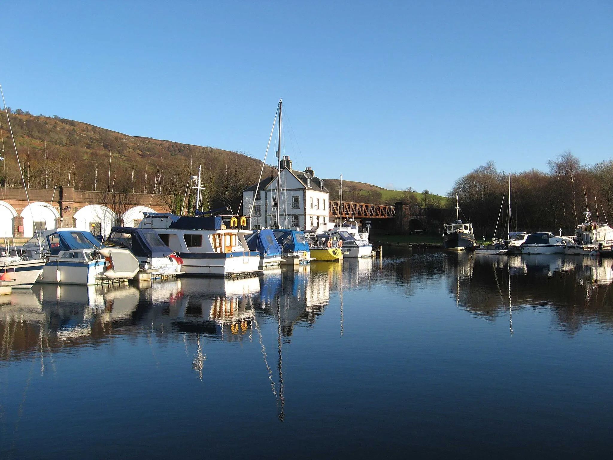 Photo showing: Bowling Basin, on the Forth and Clyde Canal at Bowling, West Dunbartonshire. The railway bridge and arches support the now disused Lanarkshire and Dunbartonshire Railway.