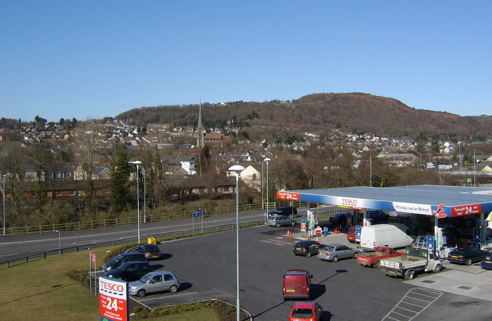 Photo showing: Pontardawe. A view of Pontardawe looking north from the footbridge over the A4067. The landmark spire of St Peter's is just left of centre.