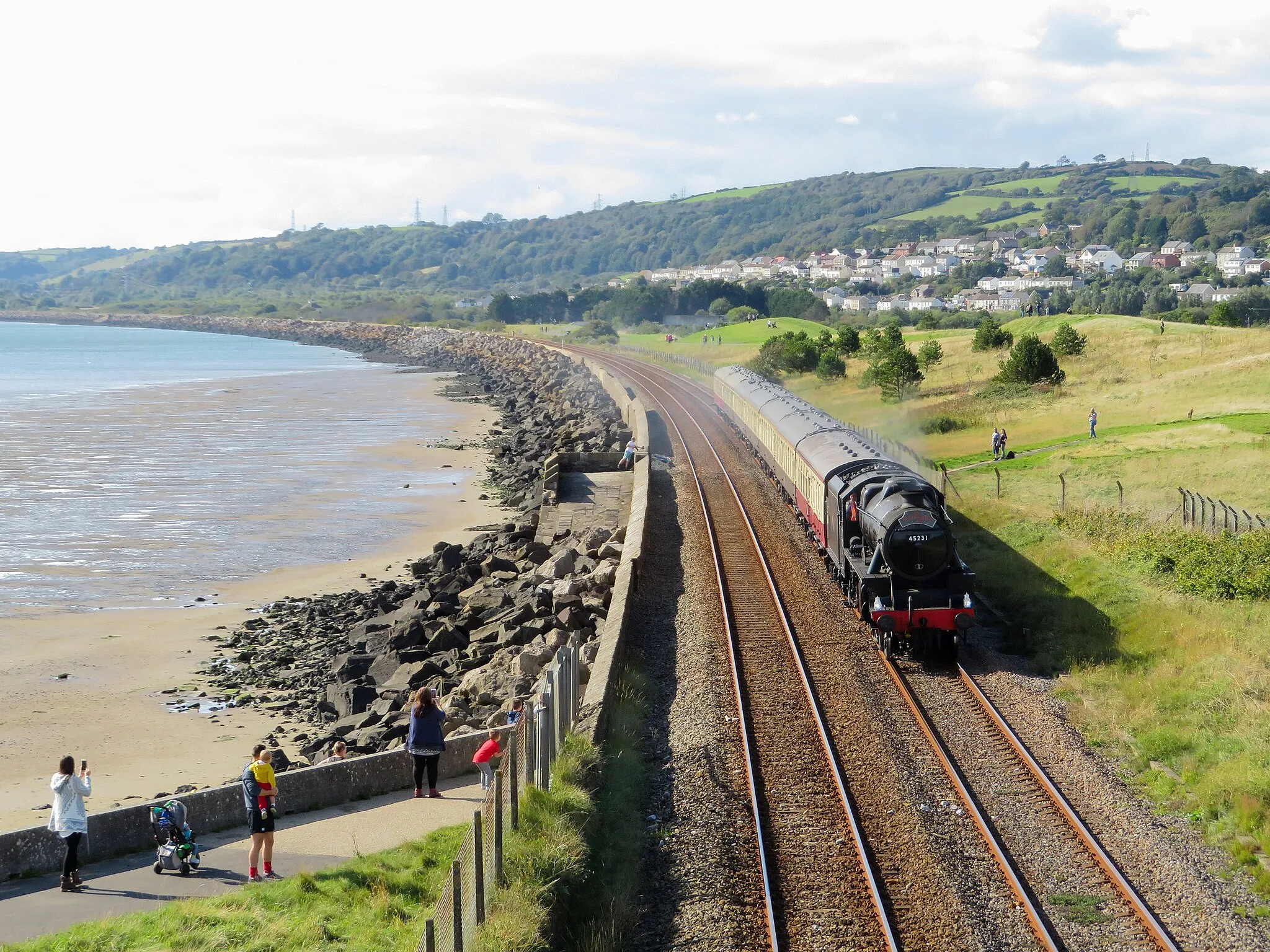 Photo showing: Black 5 near Pwll. Ex-LMS 'Black 5' No. 45231 passes Cefn Padrig near the mouth of the River Loughor, between Burry Port and Llanelli with the return leg of Pathfinder Tours' Sugar Loaf Mountaineer II railtour. The tour had originated at Birmingham, and was steam-hauled from Shrewsbury to Carmarthen and back via the Heart of Wales line.