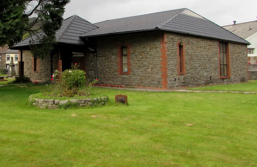 Photo showing: Parish Church of St John the Baptist, Ton Pentre. Church in Wales church in the Benefice of Ystradyfodwg in the Diocese of Llandaff. The modern church (1987) replaced the Victorian-era church of the same name on this site. St John's occupies the site of an ancient Christian hermitage founded in the 6th century.