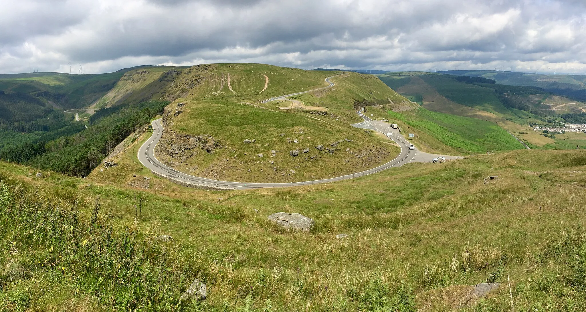 Photo showing: Bwlch y Clawdd. The A4061 links the Ogwr valley (left) with the Rhondda valley (right), with Cwmparc above Treorchy just visible.