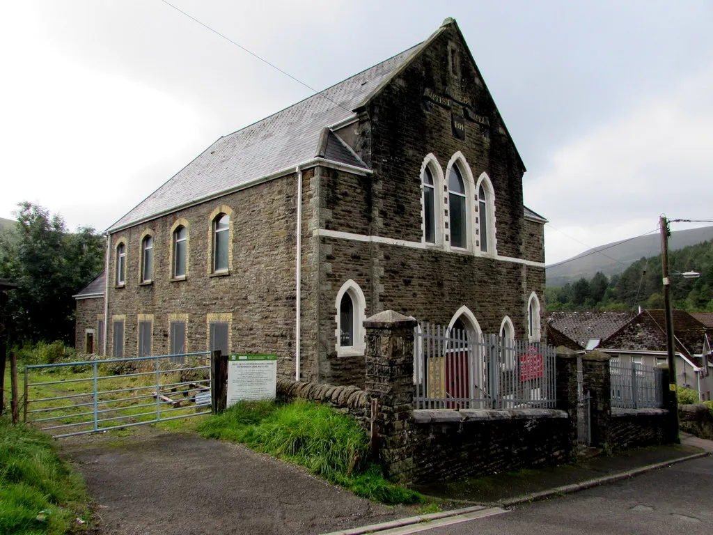 Photo showing: Horeb English Baptist Chapel, Nantymoel. Alongside Dinam Close opposite Chapel Street. In August 2018 the church nameboard shows the days and times of the weekly services here. The board also shows the other uses of the building - Sunday School, Ladies Guild, Kids Bible Club, Teen Fellowship meetings. A tablet on the wall above the upper windows shows the year 1894.