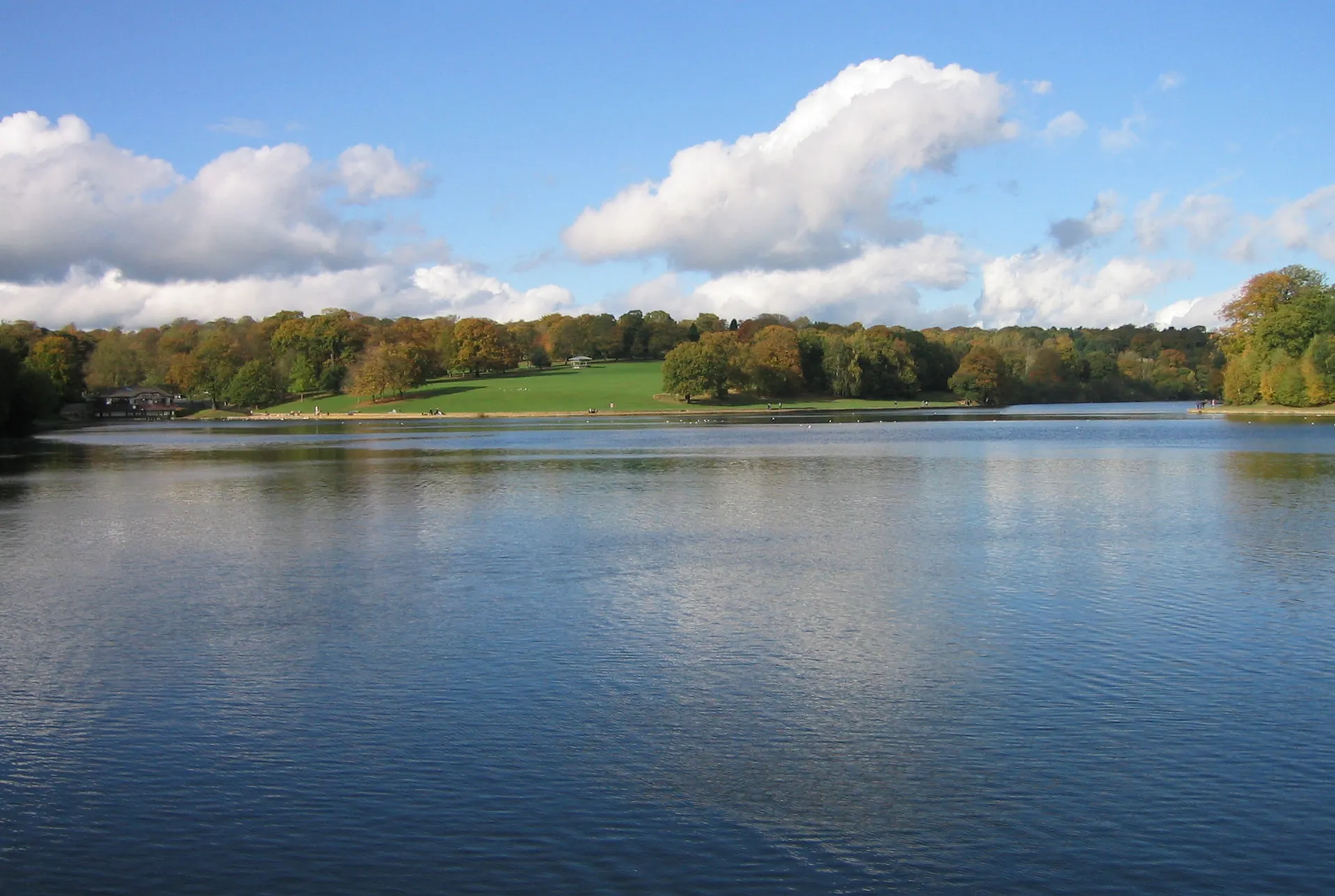 Photo showing: Waterloo Lake, Roundhay Park, Leeds.  From the dam (South) end.  Left is the Cafe, centre the Bandstand, the main length of lake ahead on right.